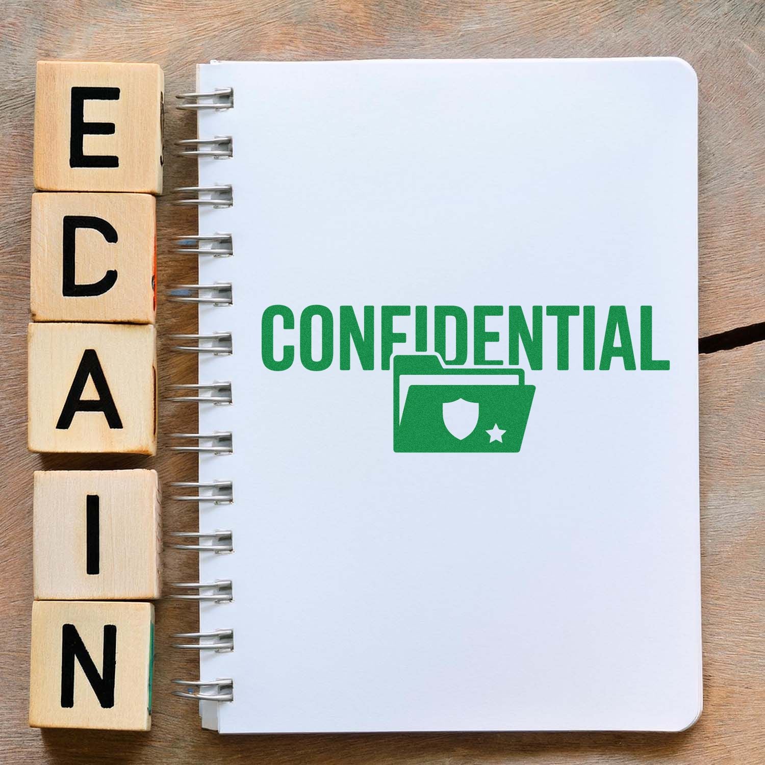Green confidential stamp and seal on a white spiral notebook, with wooden letter blocks on a wood desk.