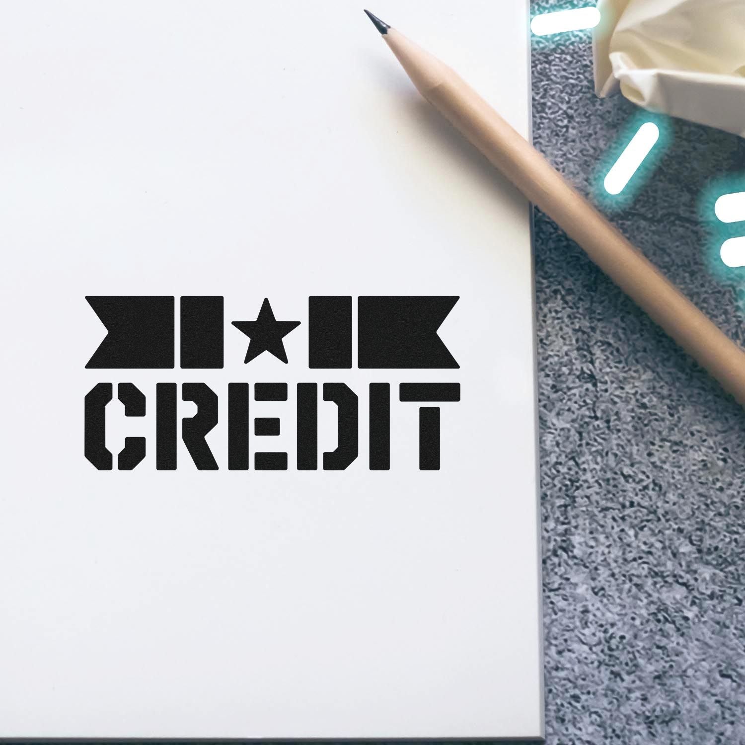 Black INK CREDIT stamp seal on white paper beside a beige pencil, with gray textured background and teal highlights.