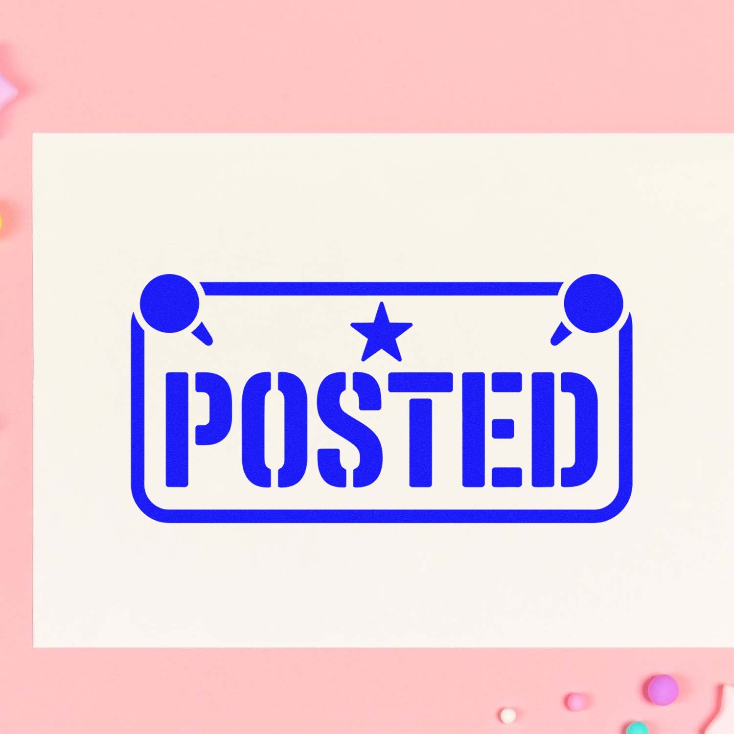 Blue POSTED stamp seal with star on a cream card, set against a soft pink background.