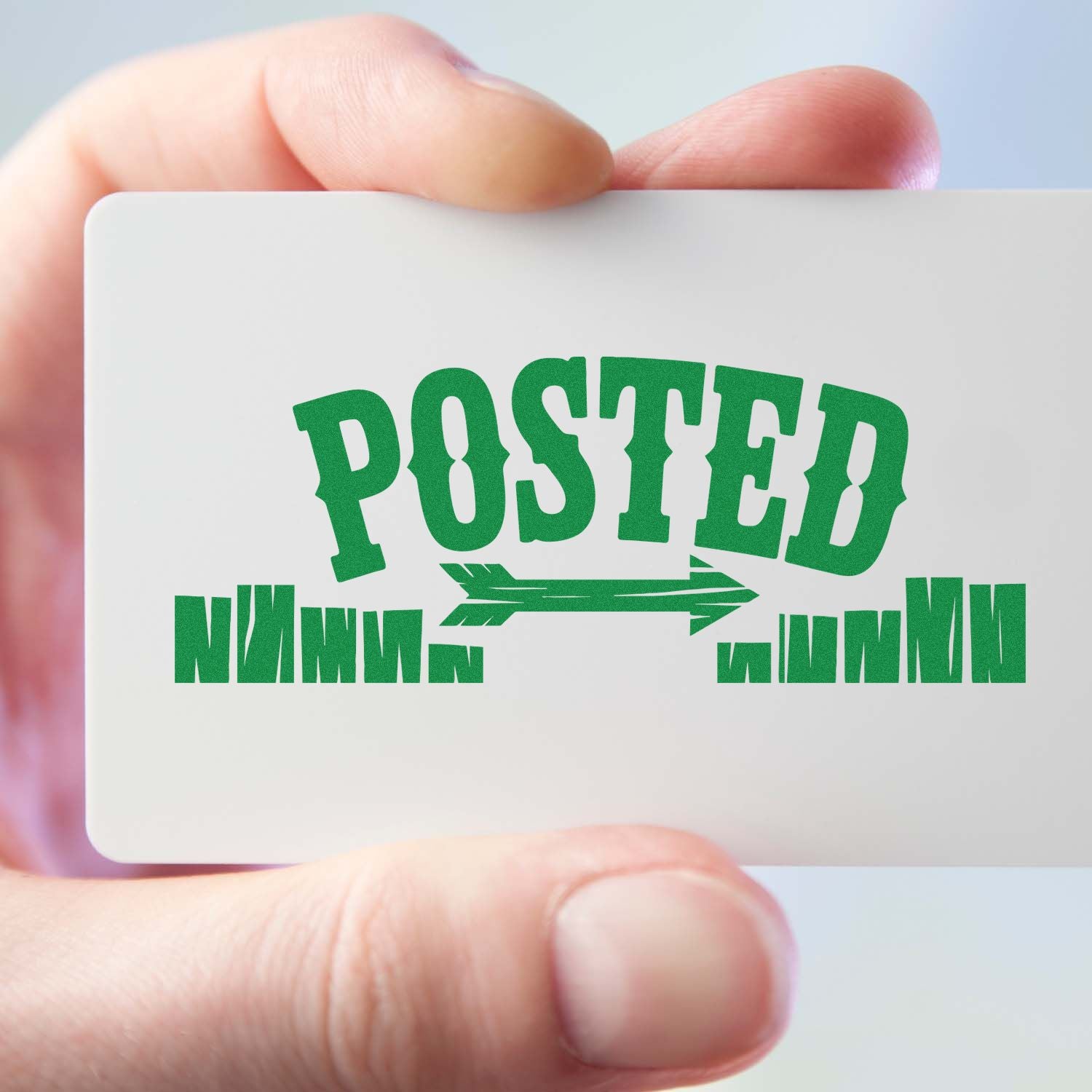 Hand holding a white stamp and seal card with green POSTED text and arrow logo