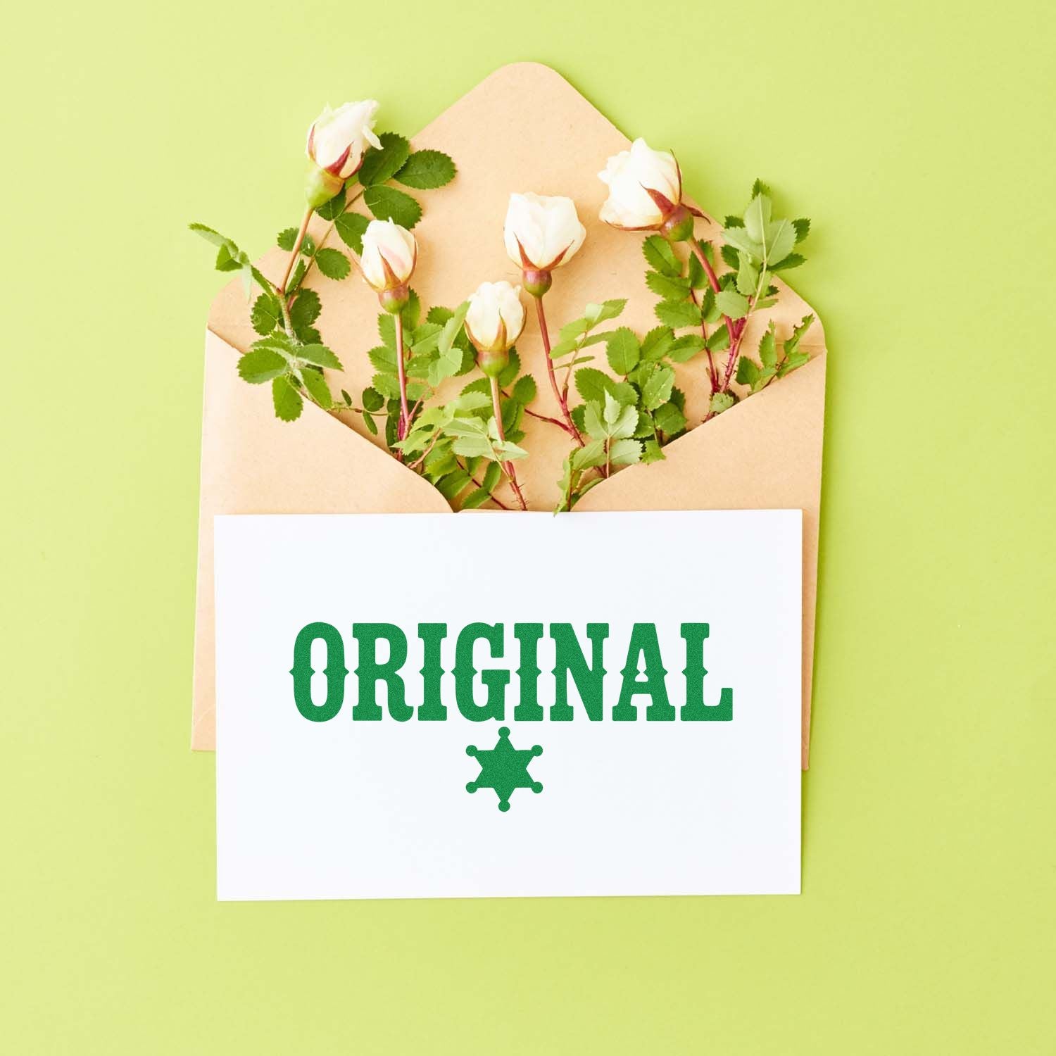 Kraft envelope with white roses and a green ORIGINAL stamp seal on a white card against a light green background.