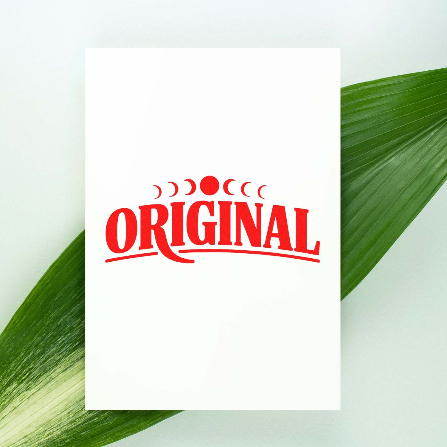 White card with red ORIGINAL stamp seal and crescent motif, framed by green palm leaves on a pale background.