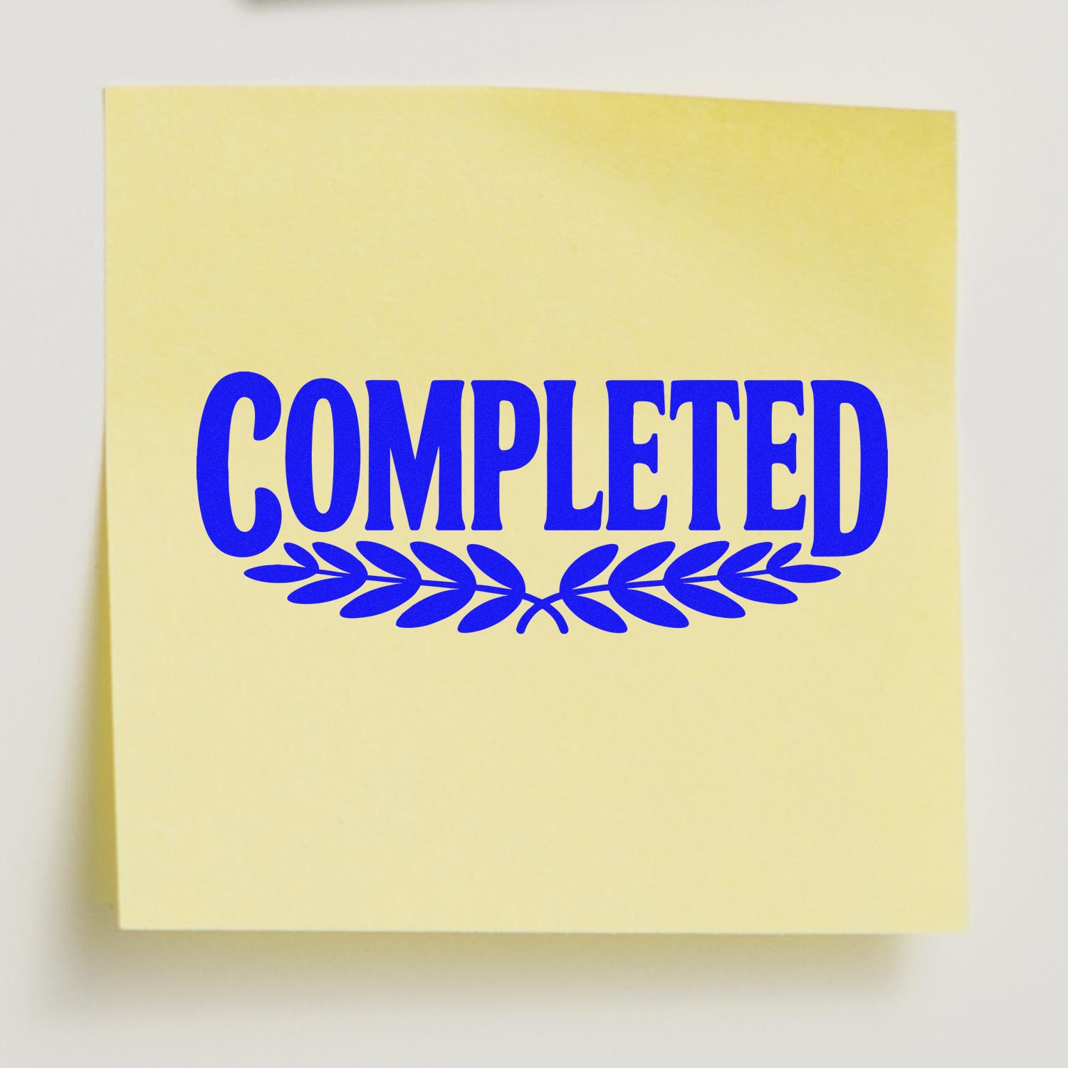 Yellow stamp seal with bold blue COMPLETED text and laurel wreath design on a pale sticky note.