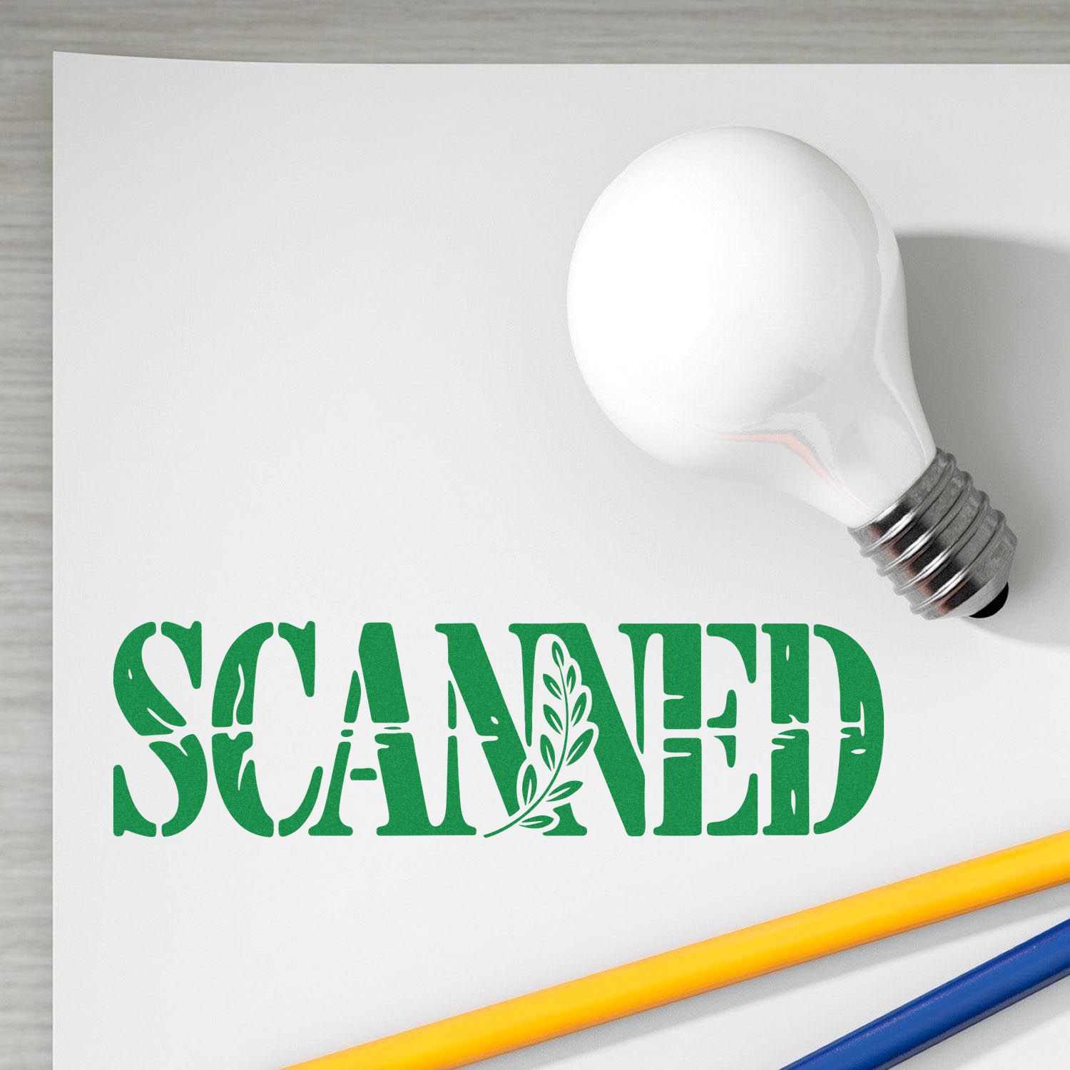 Green SCANNED stamp and white bulb-shaped seal on white paper, with yellow and blue pencils.