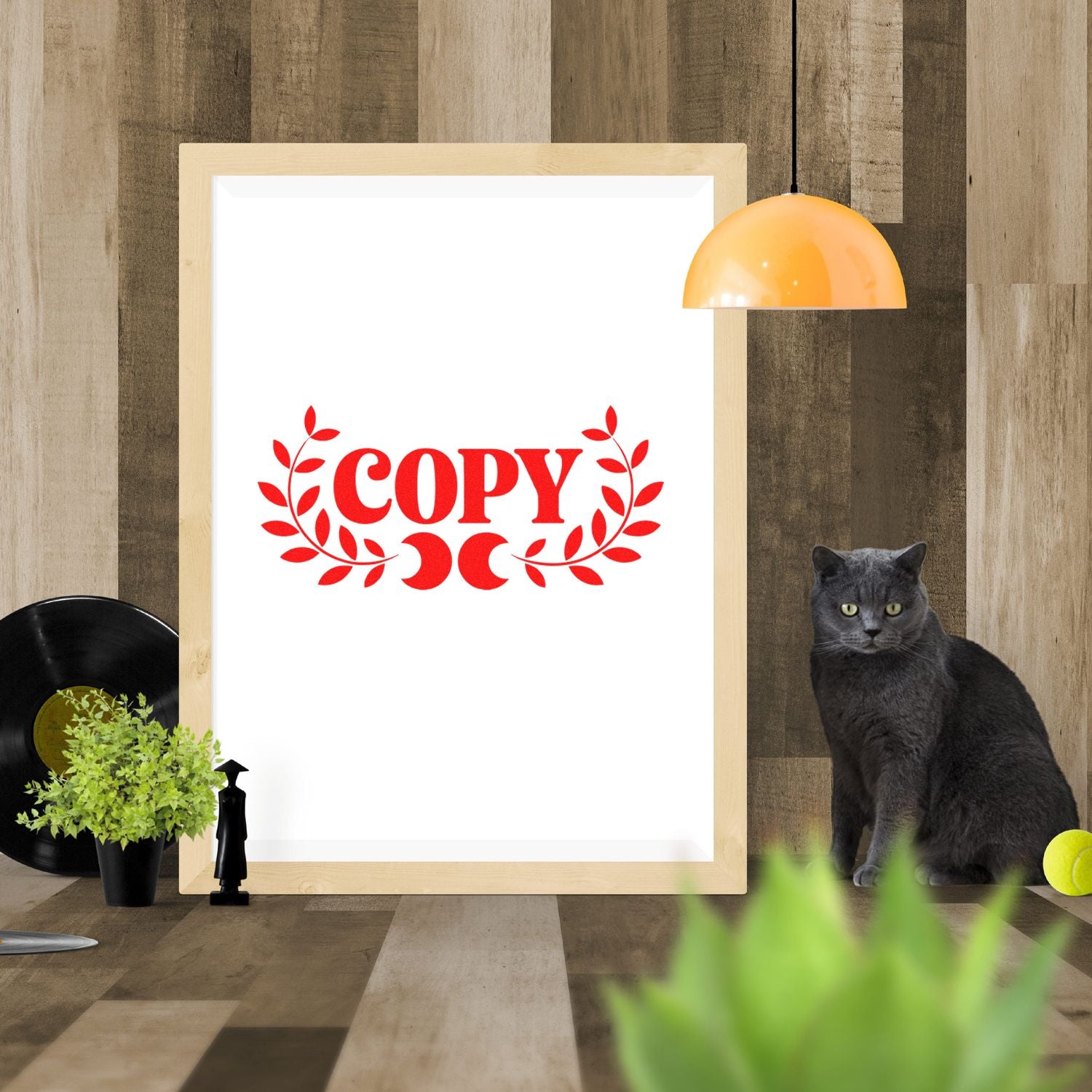 Framed white copy stamp seal with red laurel wreath on rustic wood wall, accented by a black cat.