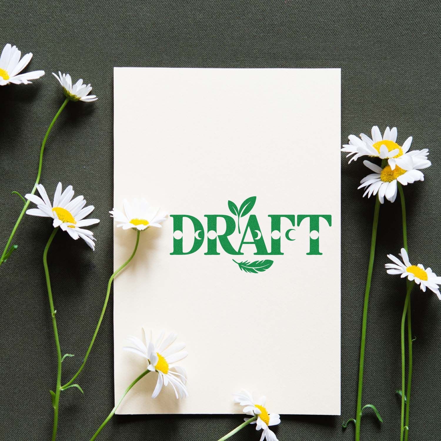 Cream blank card with green DRAFT stamp seal, framed by white daisies on dark green fabric.