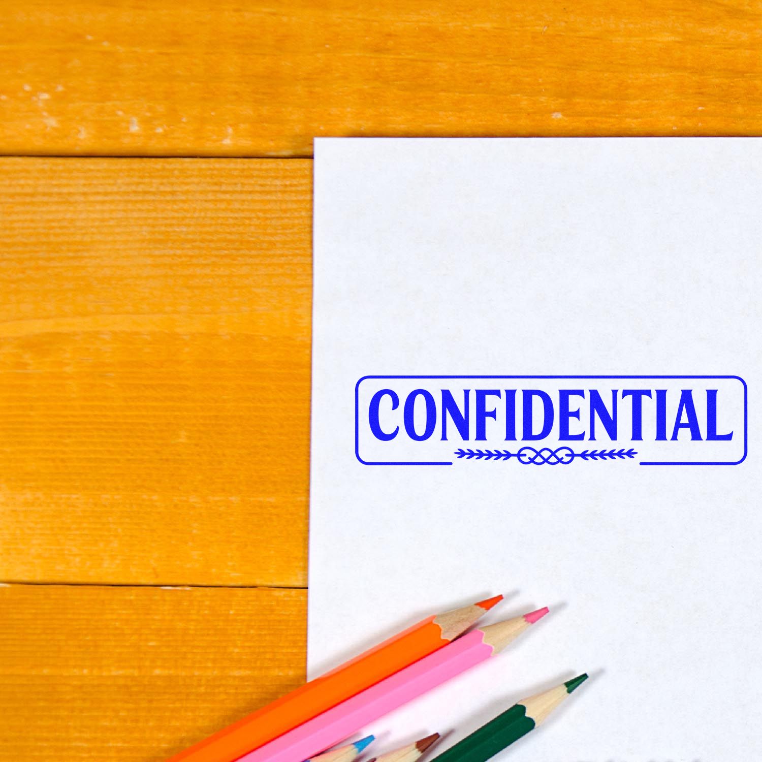 White paper with blue CONFIDENTIAL stamp seal, colorful pencils, on a warm wood table.