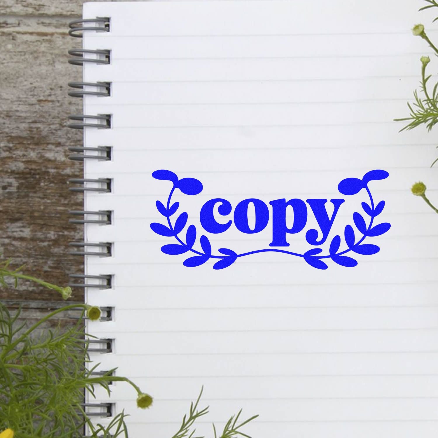 Blue copy seal stamp with floral wreath on a white spiral notebook page