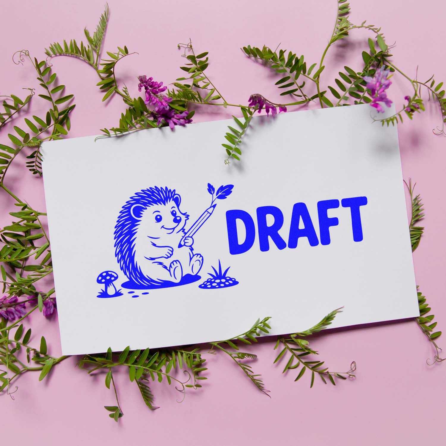Blue DRAFT stamp and seal with hedgehog holding pencil on white card, framed by green leaves and purple flowers on pink background.