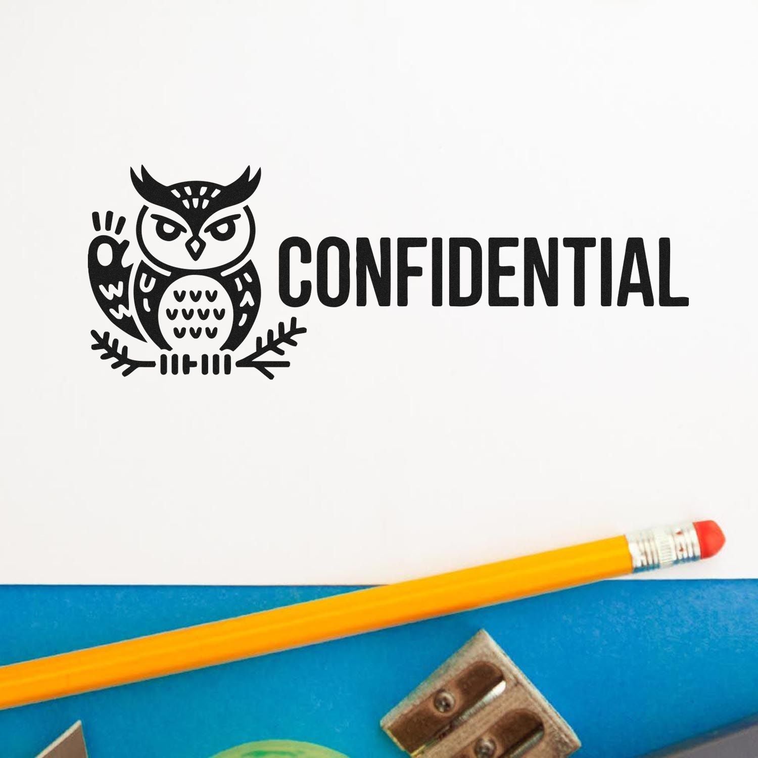 Black owl confidential stamp seal on white paper, with yellow pencil on a blue background.