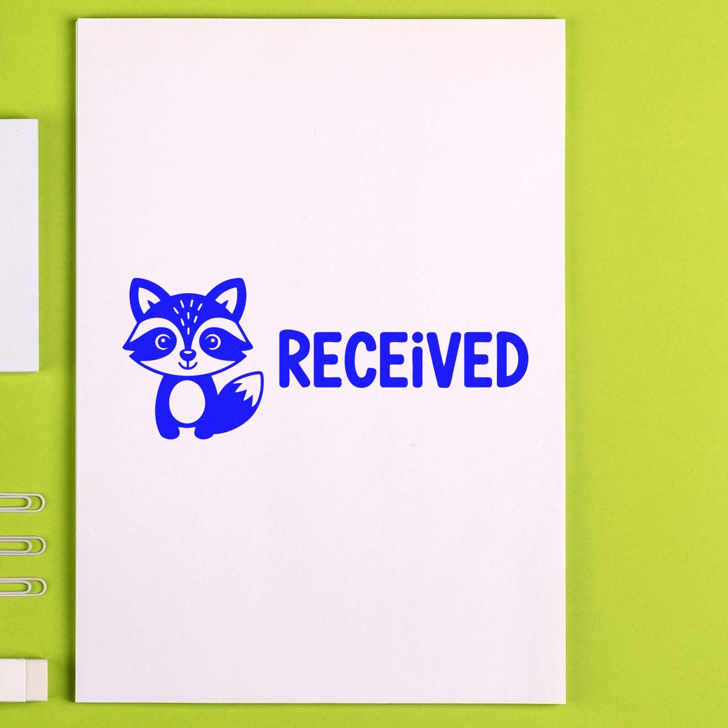 Blue raccoon RECEIVED stamp on white paper, shown on a lime green background for stamp and seal products.