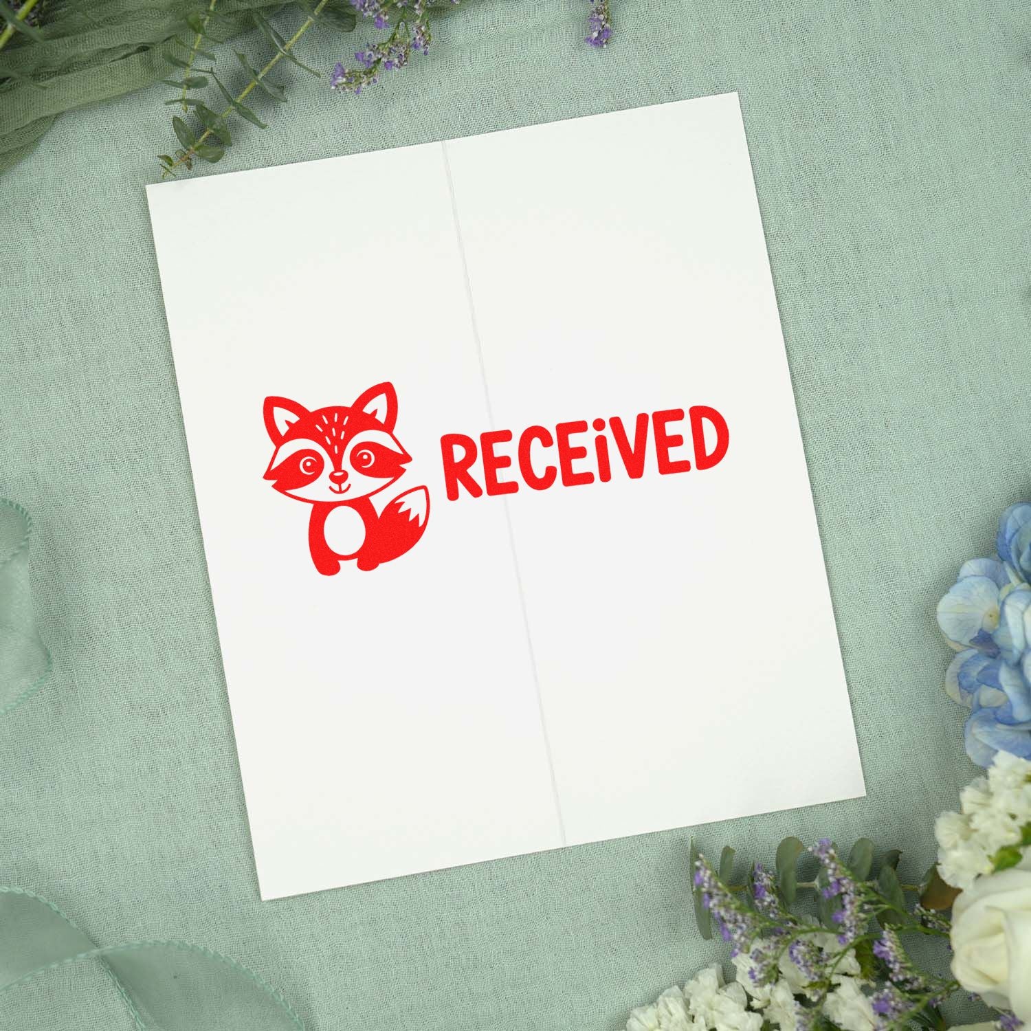 Red fox RECEIVED stamp and seal on a white envelope, styled on mint fabric with floral accents.