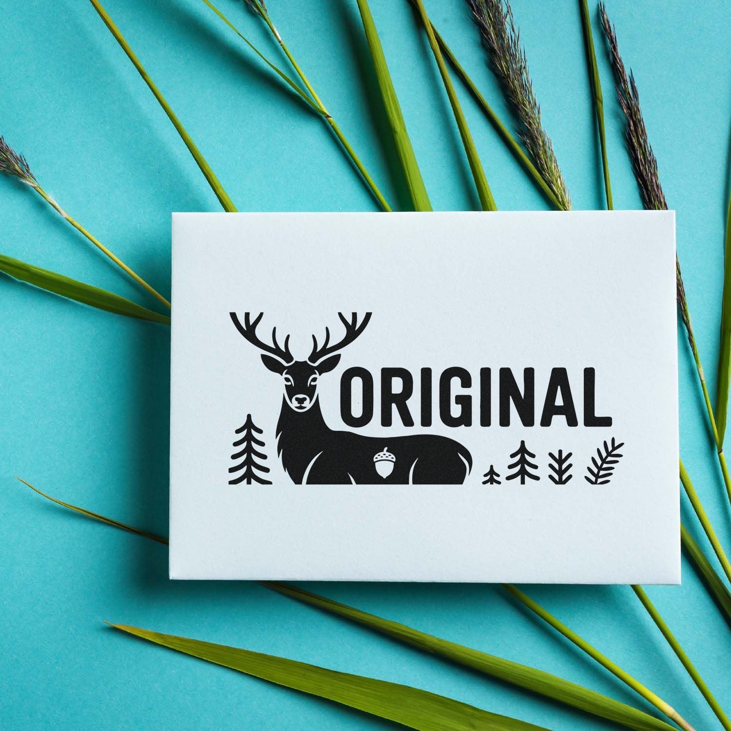 Custom black deer-and-fir stamp seal on a white card, set against a turquoise background with green grass blades.