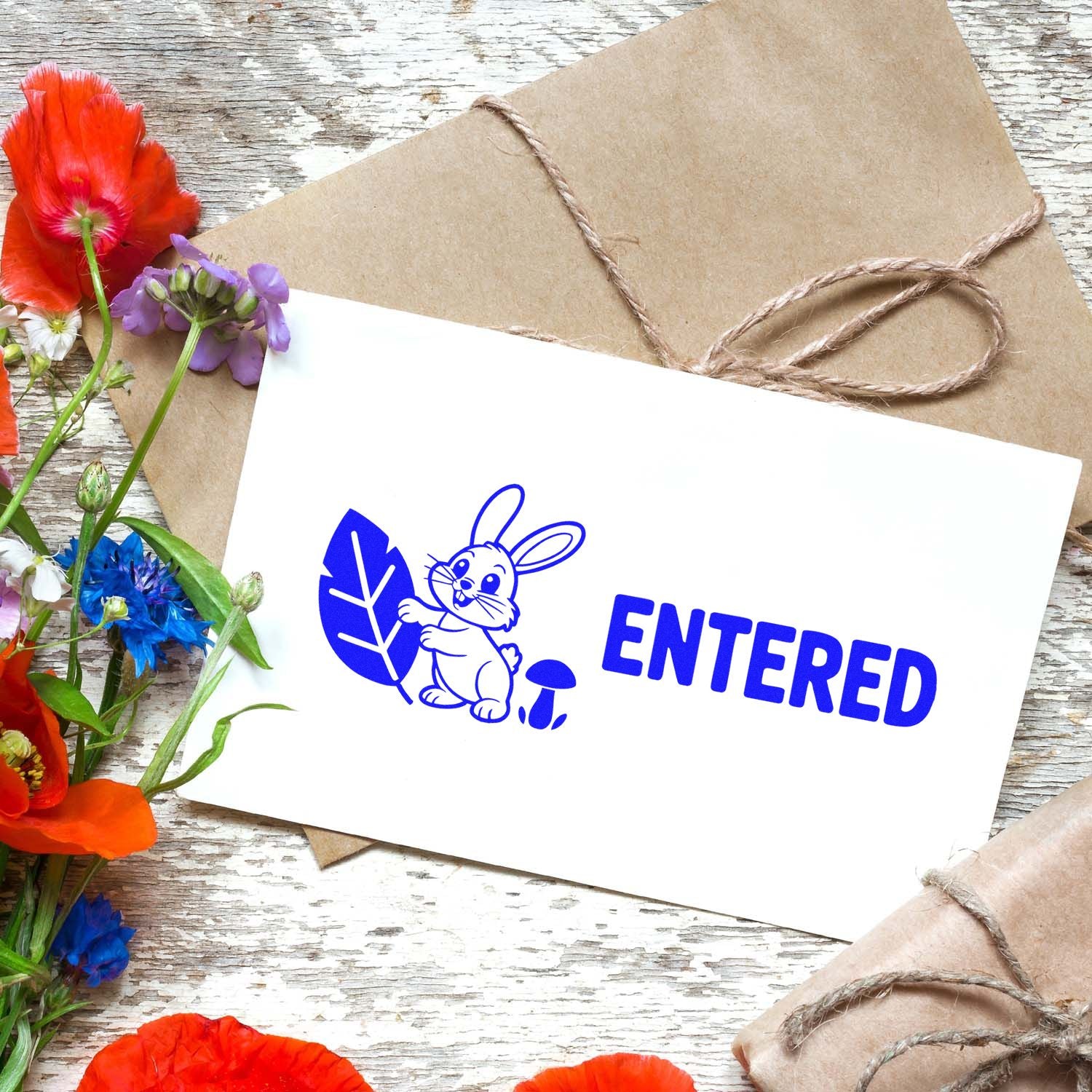 Blue bunny ENTERED rubber stamp on white card, with kraft twine wrap and bright red, purple, and blue flowers.