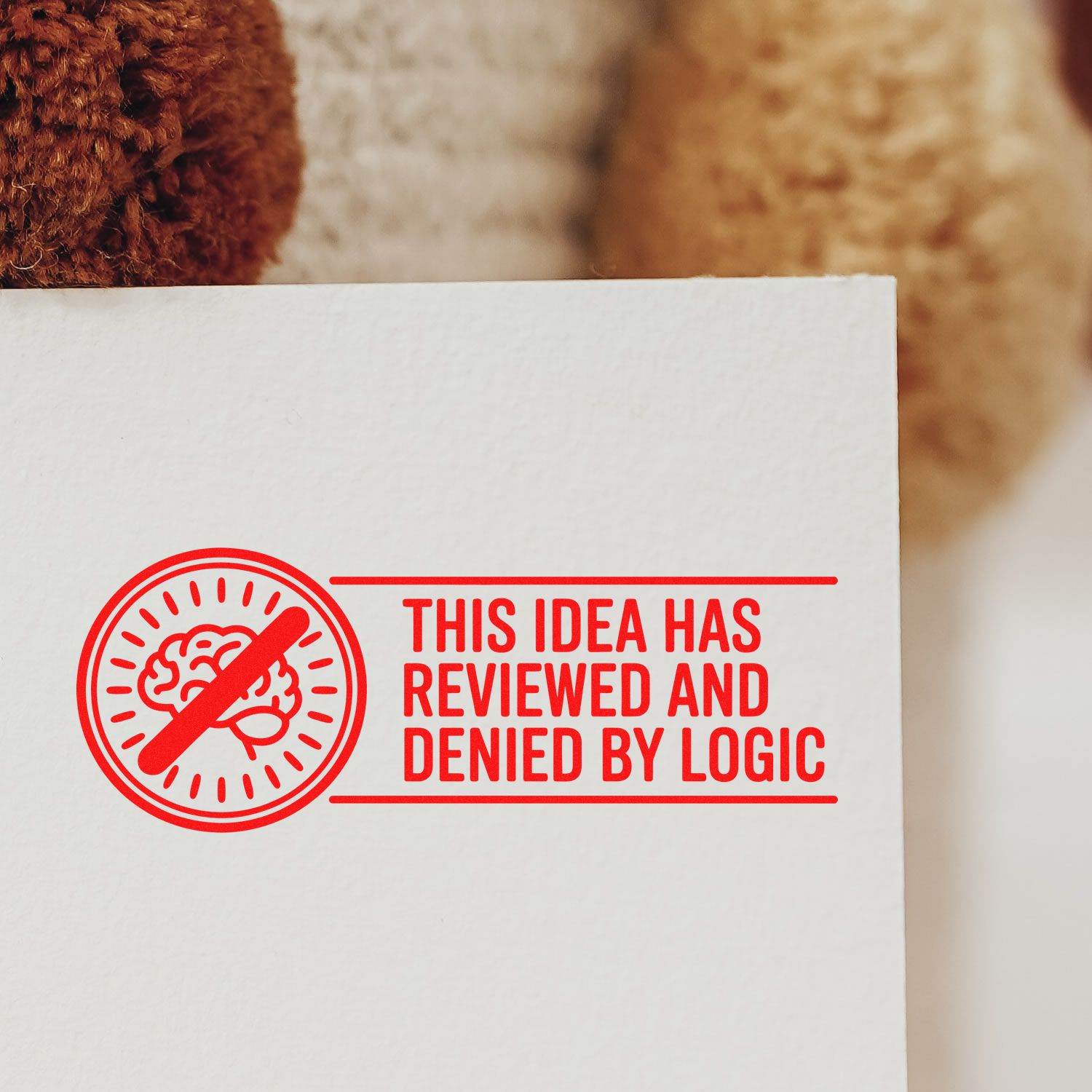 Red stamp seal with crossed-out brain icon and bold This idea has reviewed and denied by logic text on white paper.