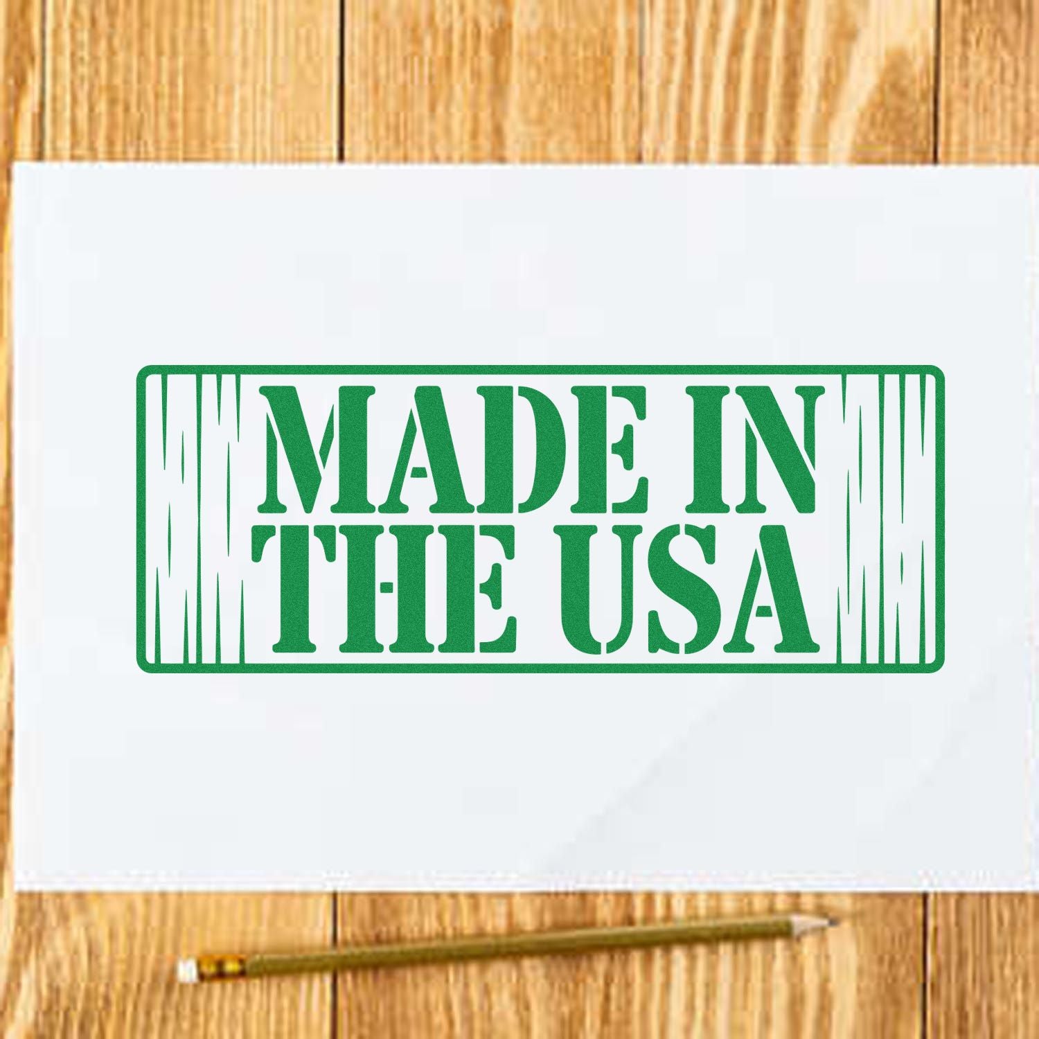 Green Made in the USA rubber stamp impression on white paper, with a pencil on a wood tabletop.
