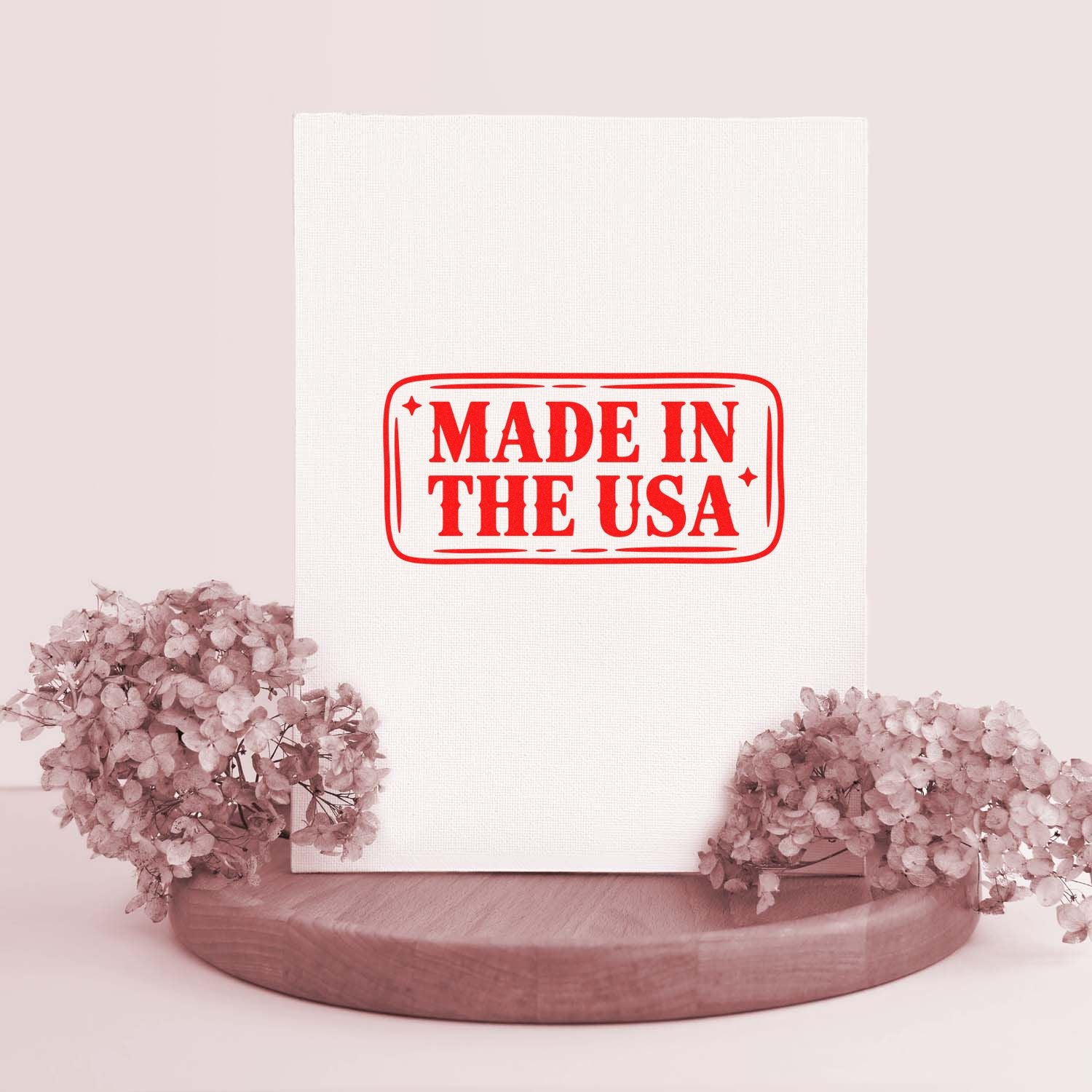 White stamp-and-seal package with bold red Made in the USA seal, on a wood base with blush pink flowers.