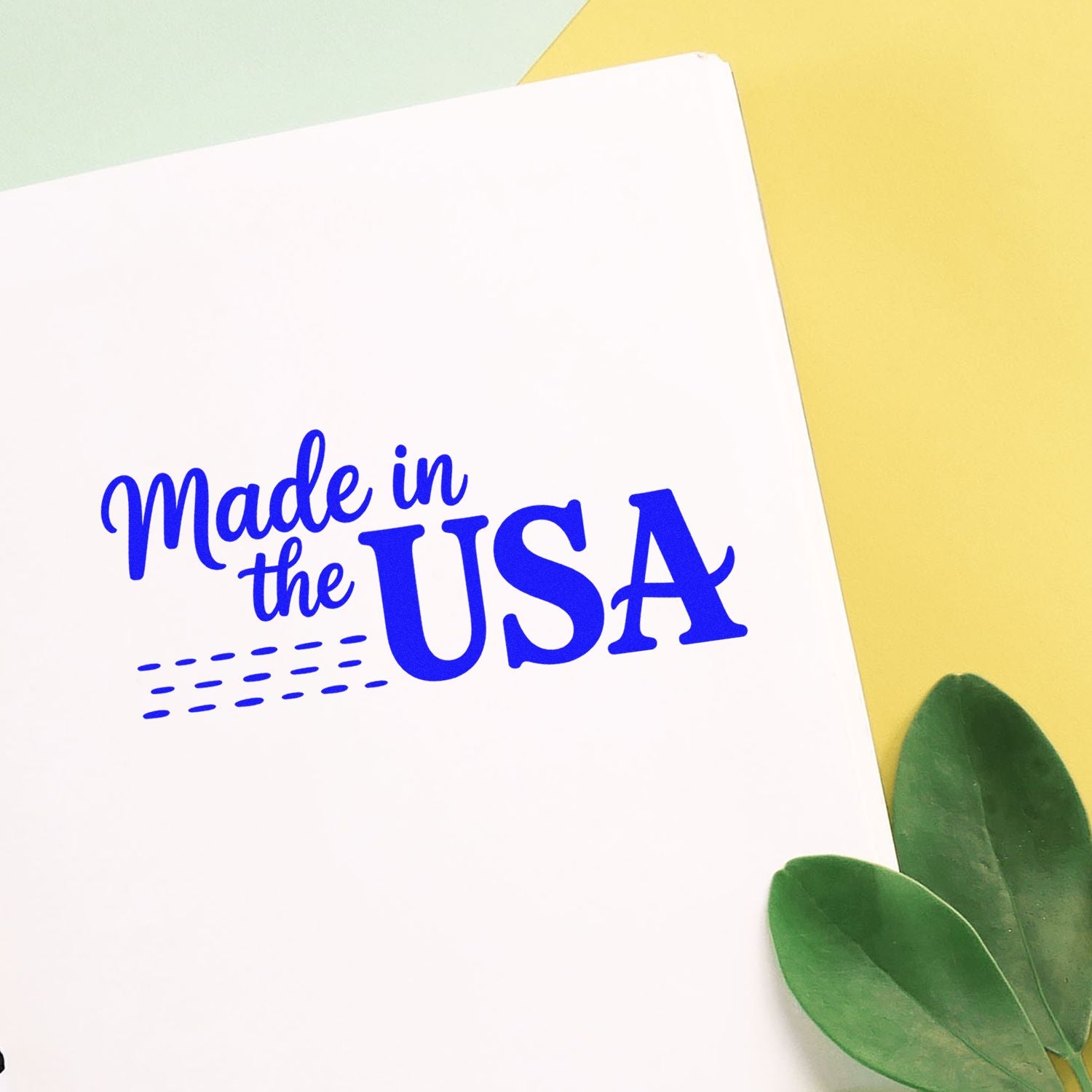 Blue Made in the USA stamp/seal on white paper, with a yellow background and green leaves.