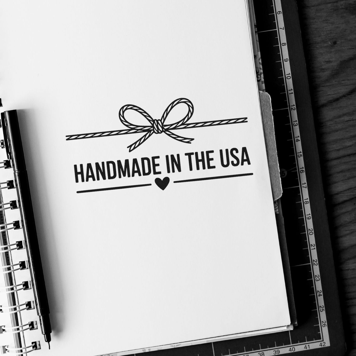 Black-and-white handmade in the USA stamp and seal design with rope bow, heart, and bold text on white paper.
