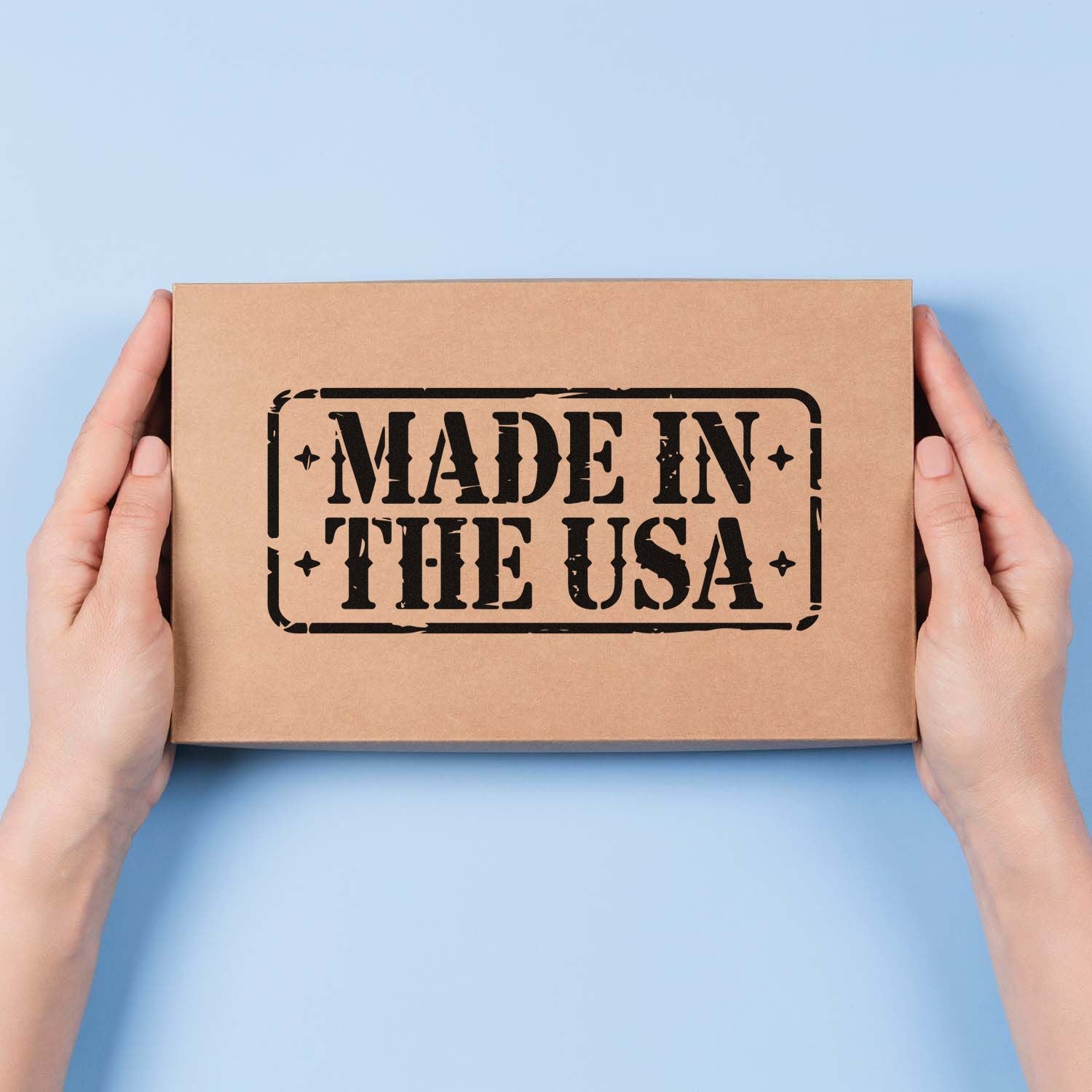 Hands holding kraft box with black Made in the USA stamp seal on a light blue background.