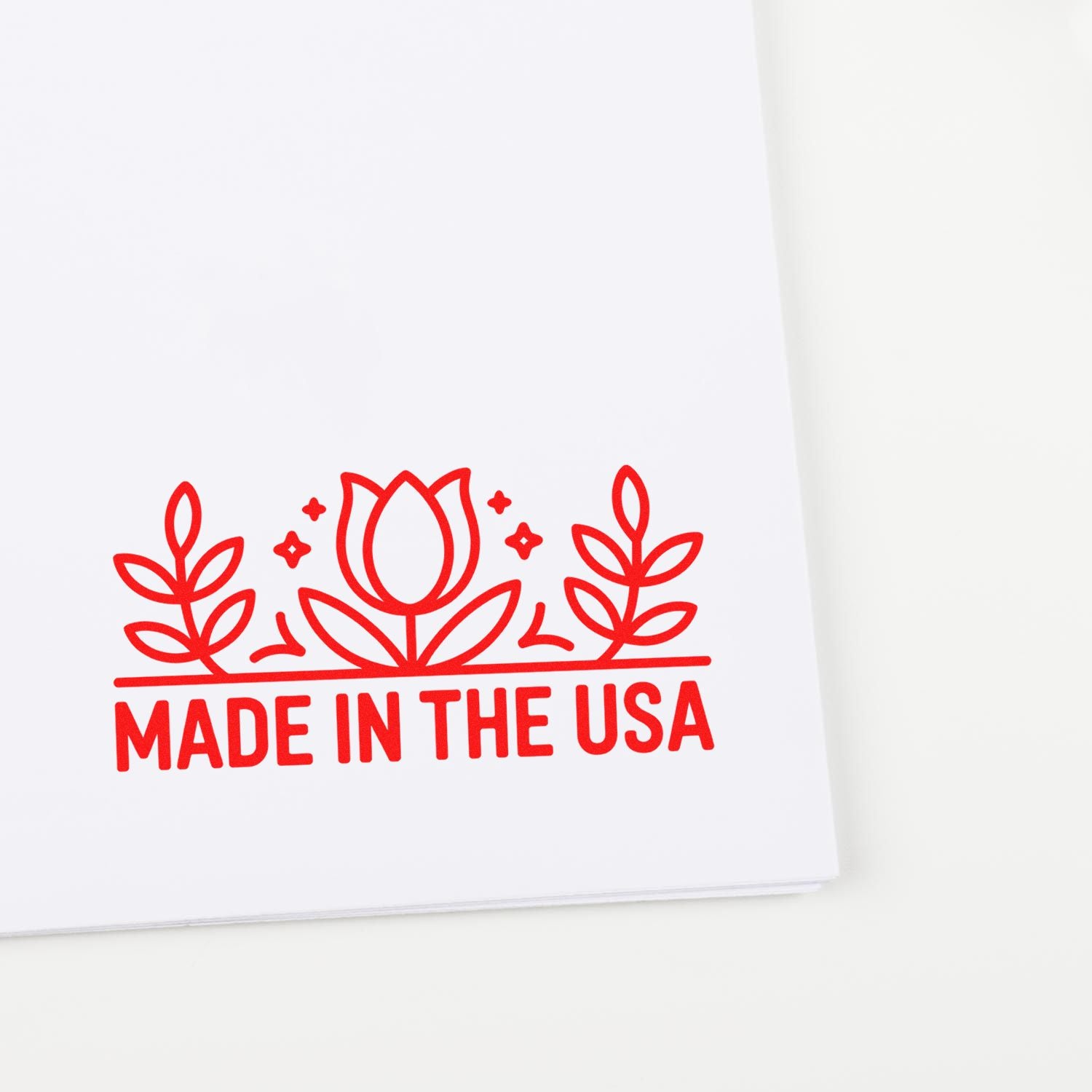 Red floral Made in the USA stamp seal with tulip and leaves on white paper.