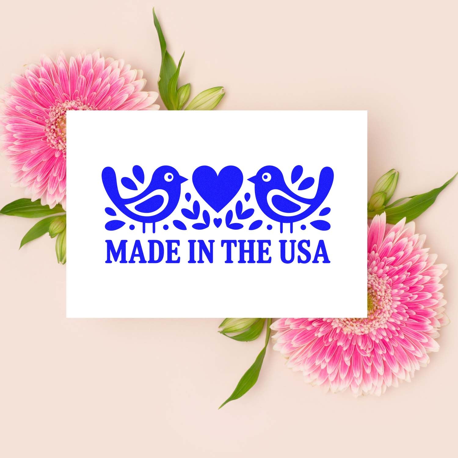 Blue Made in the USA stamp seal with two birds and heart, on a white card with pink flowers and green leaves.
