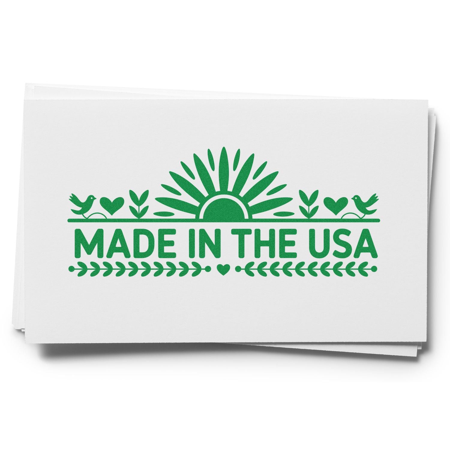 Green Made in the USA stamp seal on white paper stack, with sunburst, birds, hearts and leaf accents.