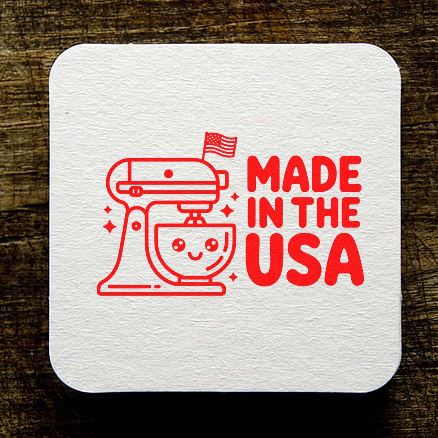 White textured stamp and seal with red stand mixer, U.S. flag, and bold Made in the USA text on wood.
