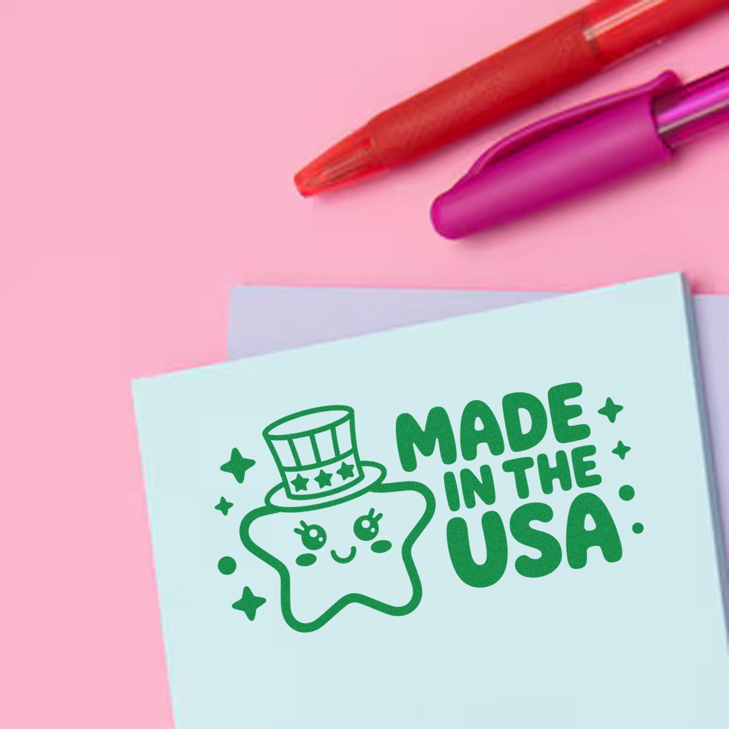 Pink and purple stamp and seal pens above a light blue card stamped green Made in the USA with a star mascot.