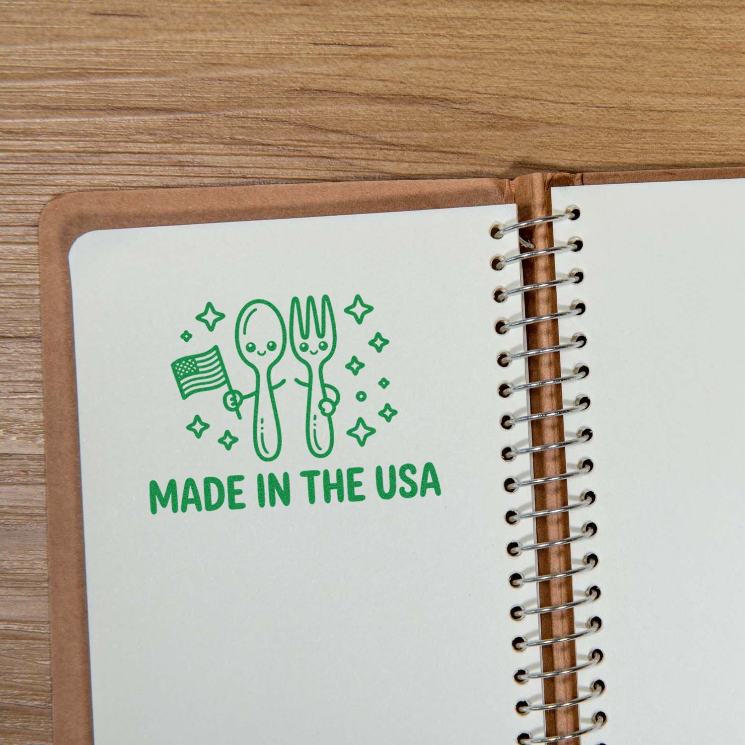 Green Made in the USA stamp and seal with smiling spoon and fork, stars, and US flag on a spiral notebook.