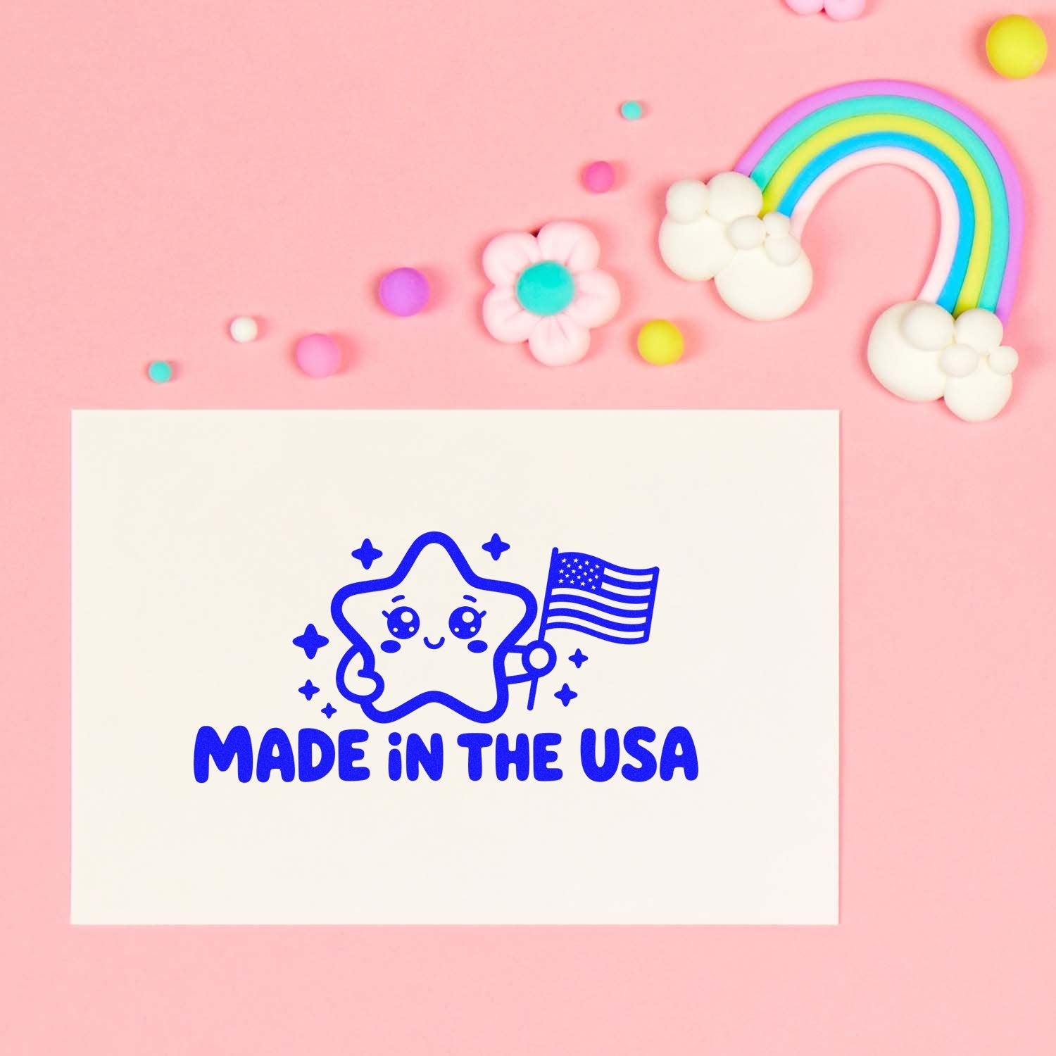 Blue Made in the USA stamp seal with cute star and U.S. flag on white card, set on pink background with pastel rainbow accents.