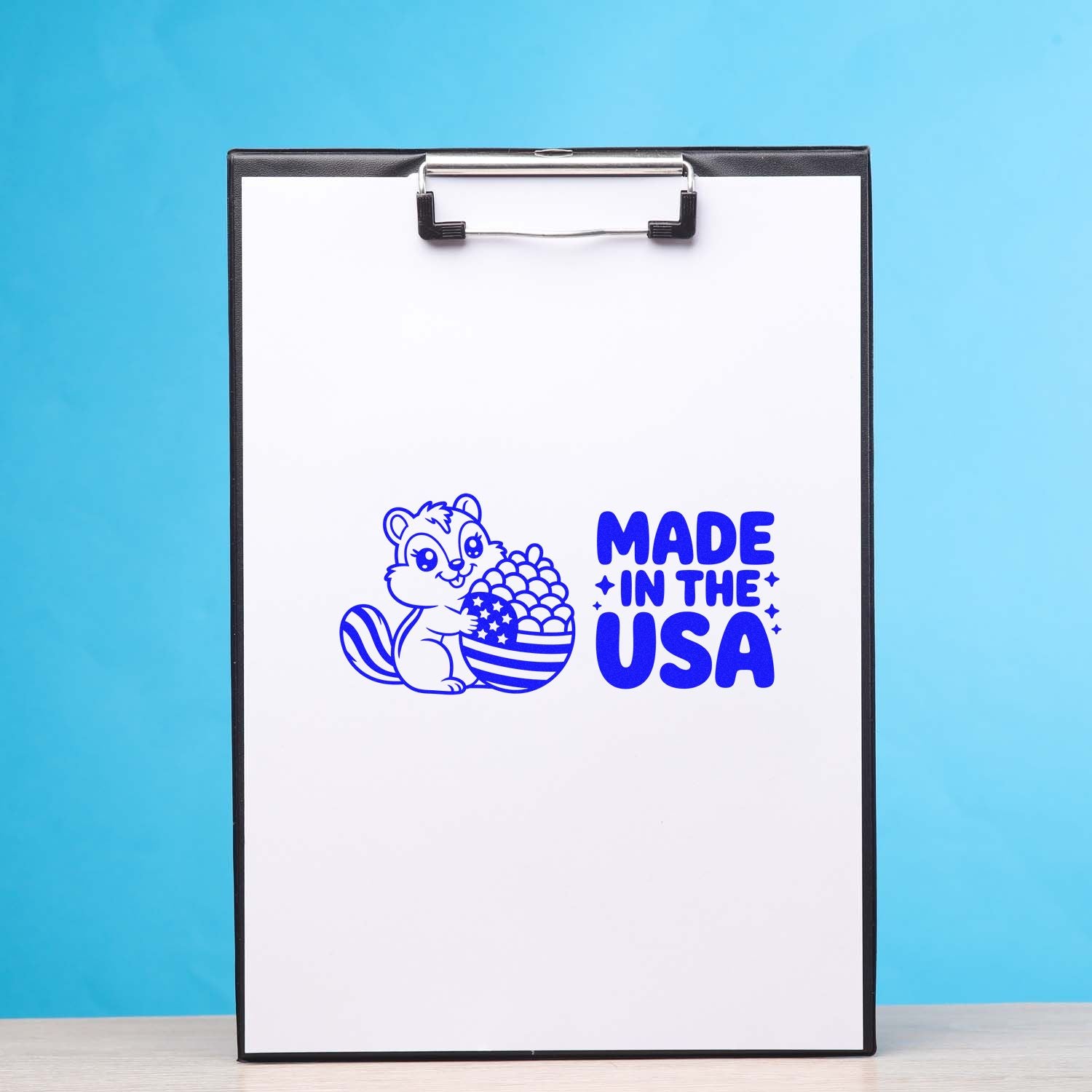 Blue Made in the USA stamp seal with squirrel and patriotic acorn on a white clipboard, black frame.
