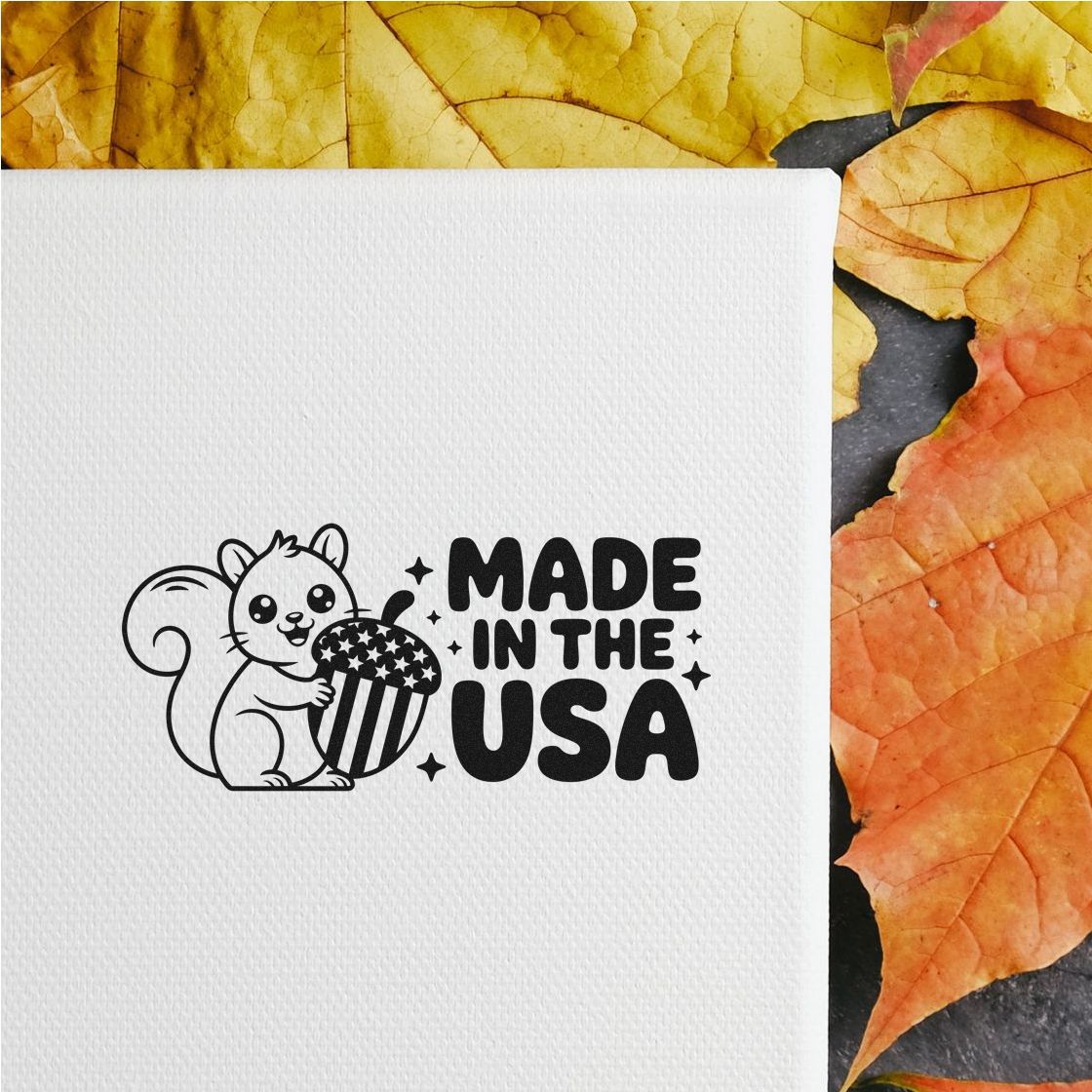 Black Made in the USA stamp seal with squirrel and patriotic acorn on white paper, framed by yellow and orange autumn leaves.