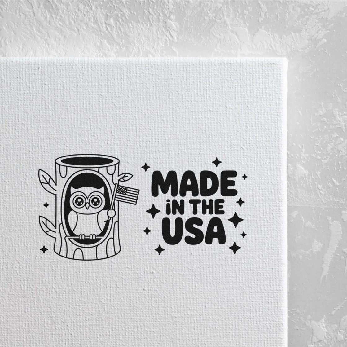 Black Made in the USA stamp seal featuring an owl in a tree stump holding a small American flag on white canvas.