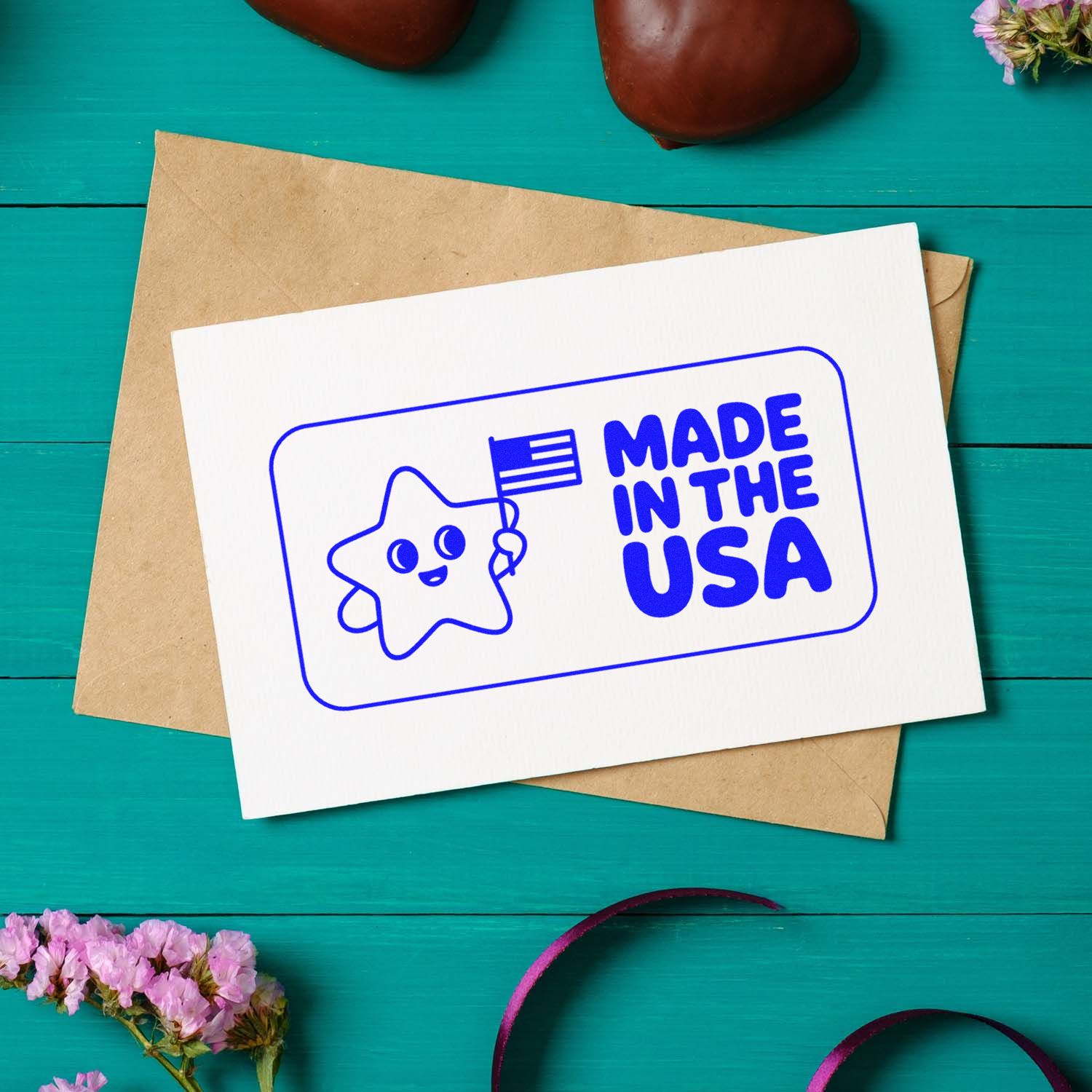 Blue Made in the USA stamp and seal on a white card over a kraft envelope on a teal wood background.