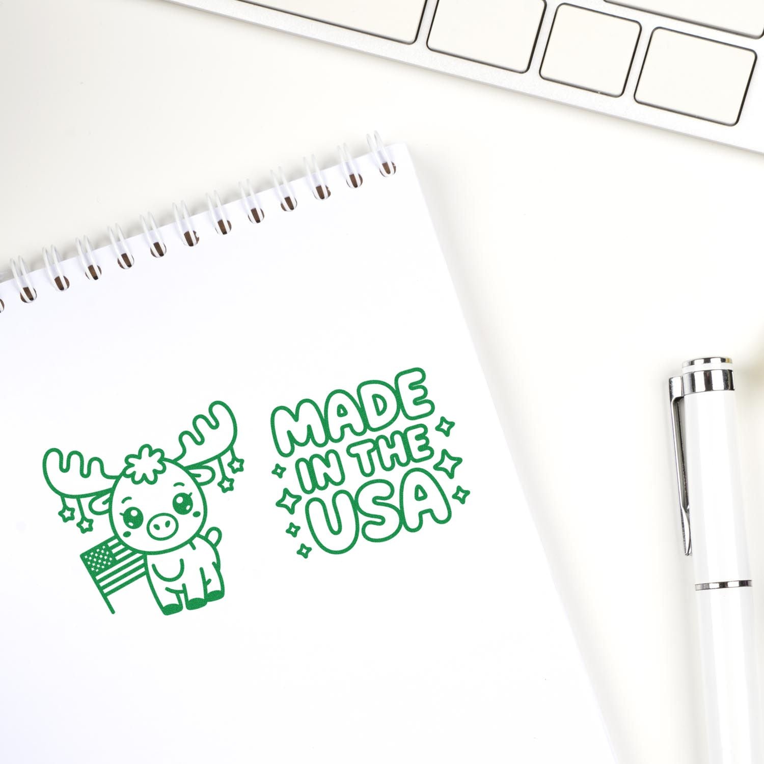 Green custom stamp and seal design on white notebook page, featuring a cute moose and Made in the USA text.