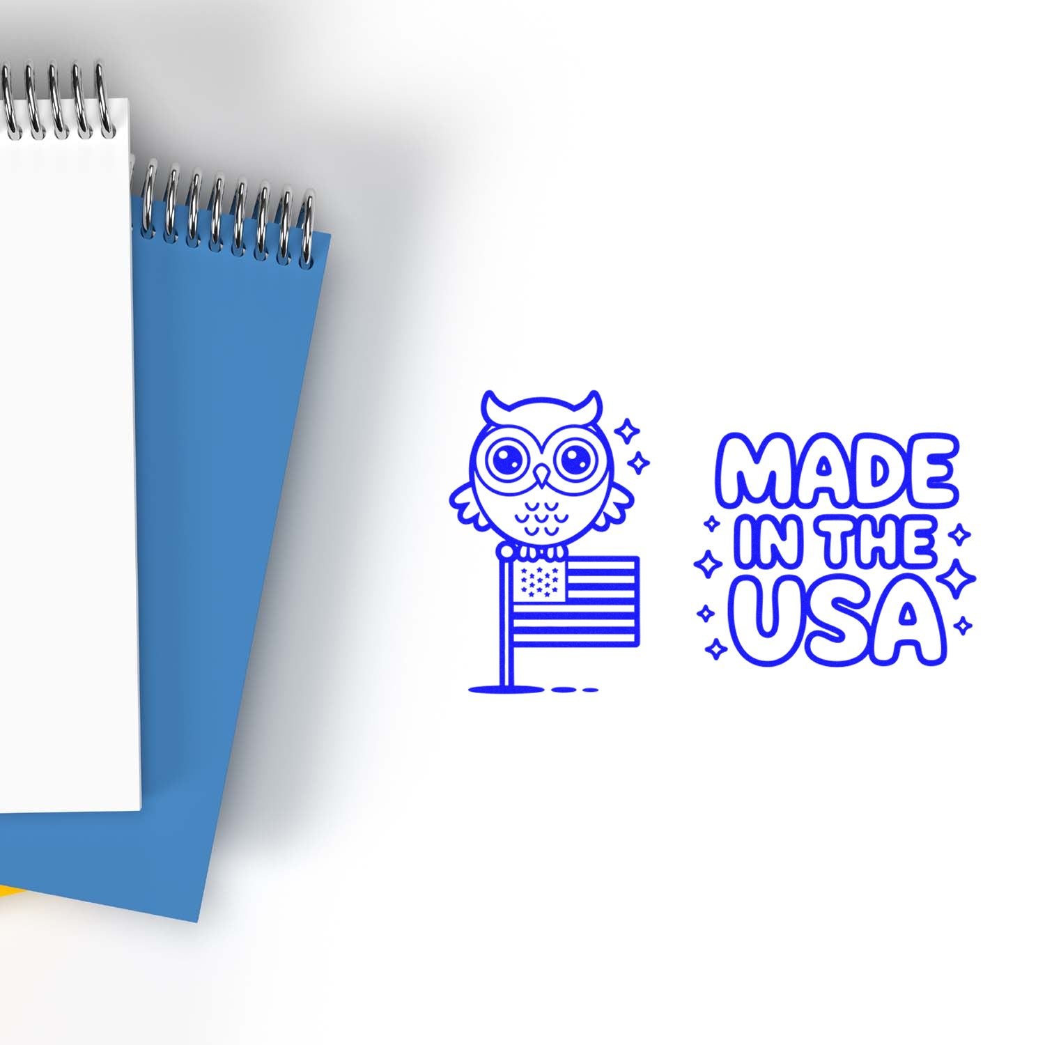 Blue custom stamp seal with owl and U.S. flag, reading Made in the USA, beside white and blue spiral notebooks.