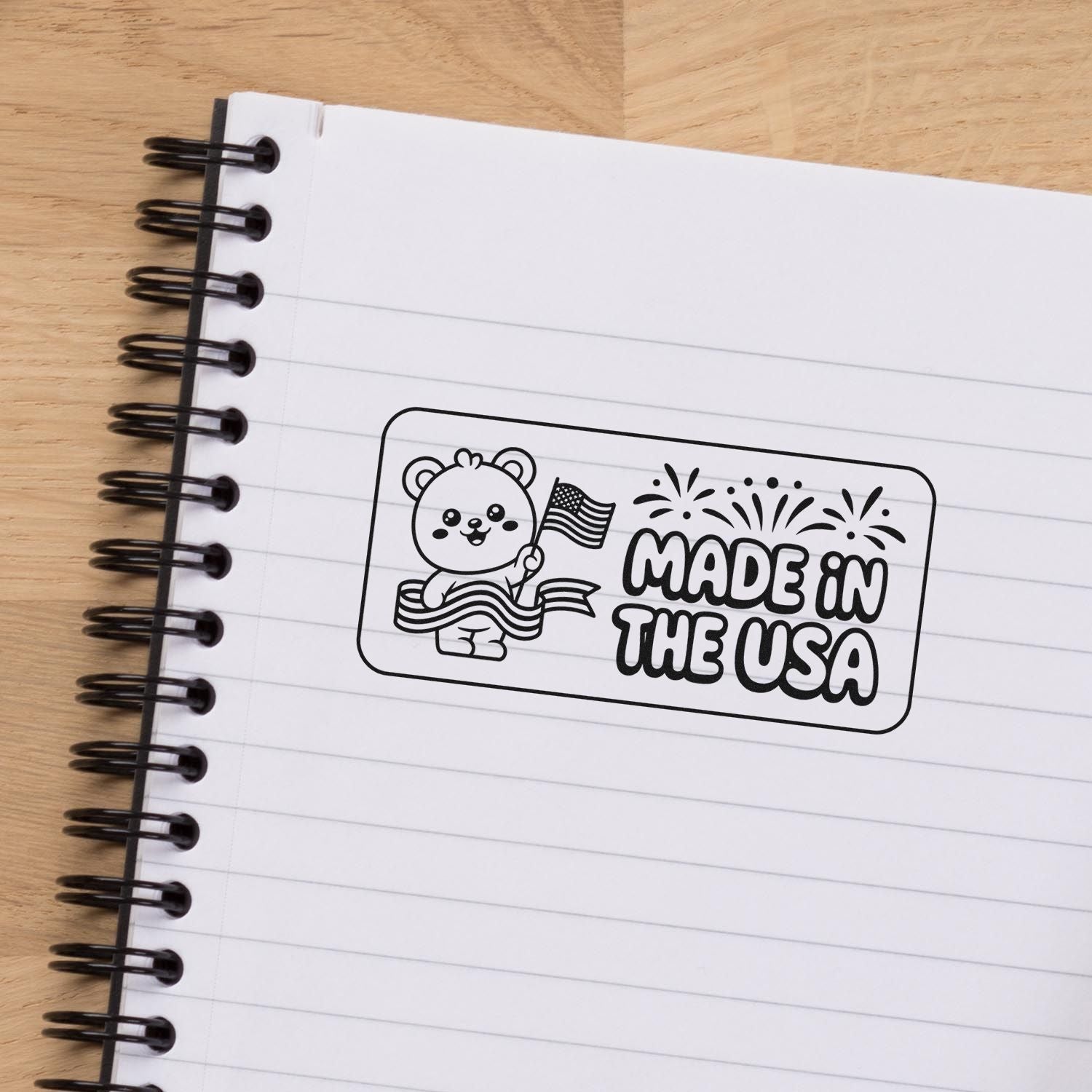 Black-and-white Made in the USA stamp seal with bear, flag and fireworks on a lined spiral notebook
