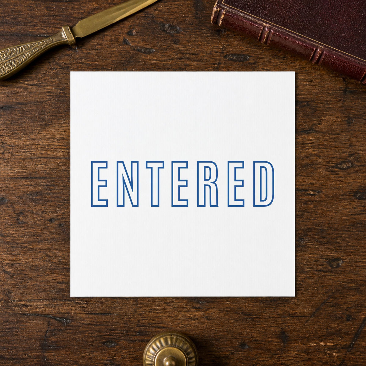 Pre-inked "Entered" stamp marking paperwork in an office setting