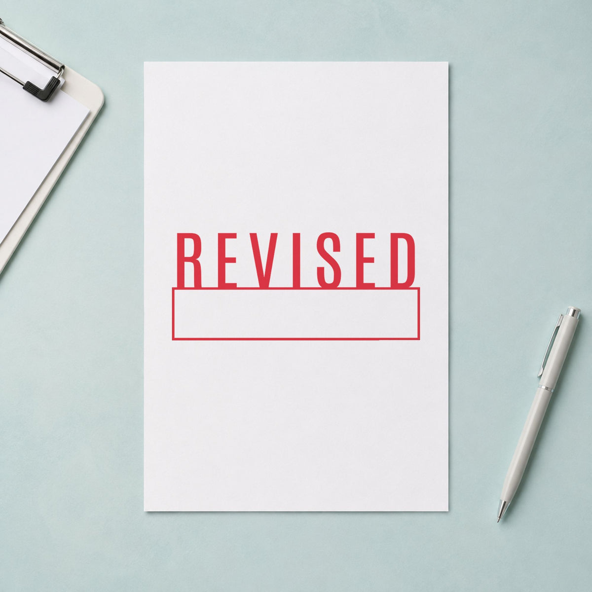Pre-inked "Revised" stamp marking paperwork in an office setting