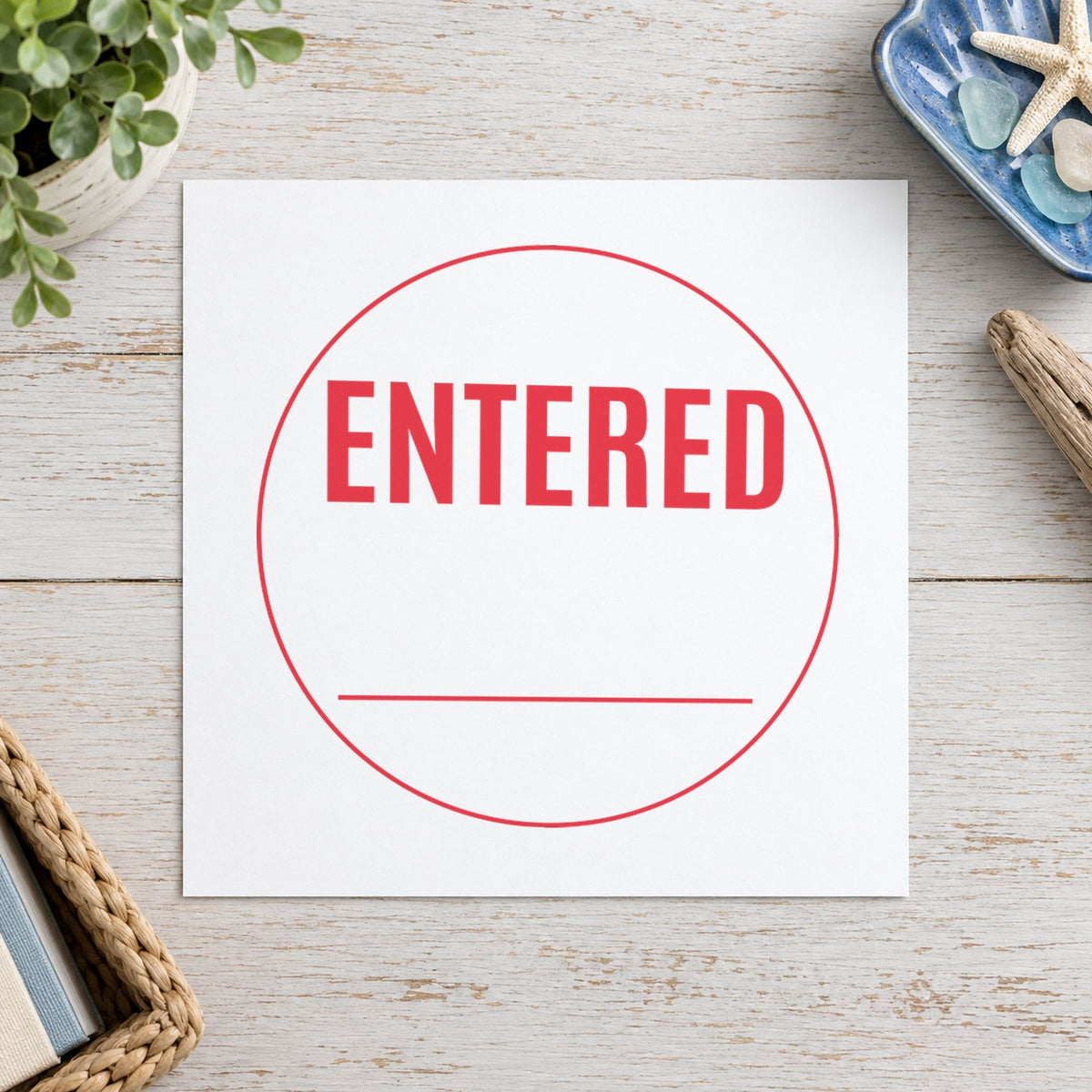 Pre-inked "Entered" stamp marking paperwork in an office setting