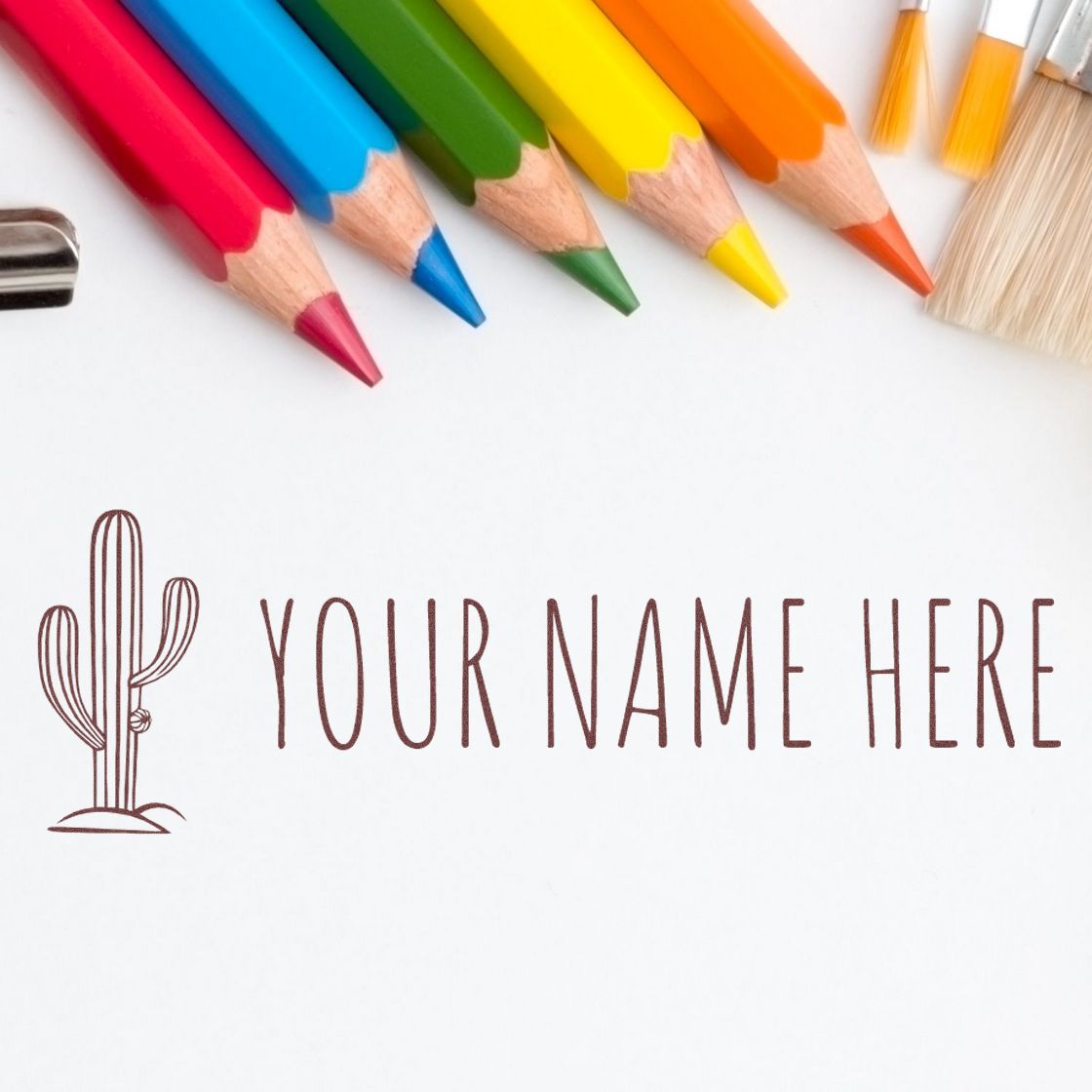 Personalized cactus stamp and seal with brown text on white paper, framed by colorful pencils and brushes.