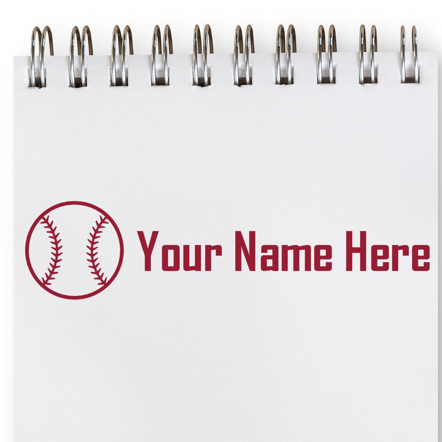 Red baseball-themed custom stamp and seal on white spiral notebook page with Your Name Here text.