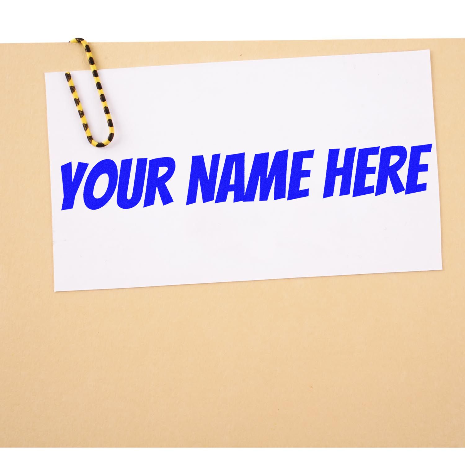 Custom stamp and seal card with bold blue YOUR NAME HERE text, clipped with a black-yellow paperclip on beige.