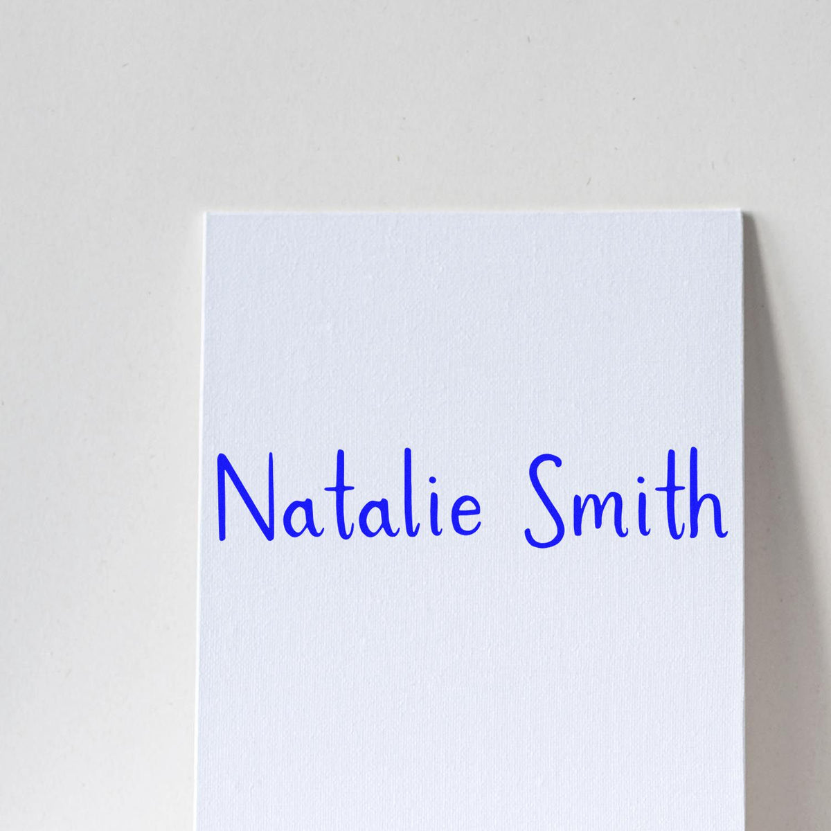 White custom stamp and seal card with blue handwritten Natalie Smith lettering.