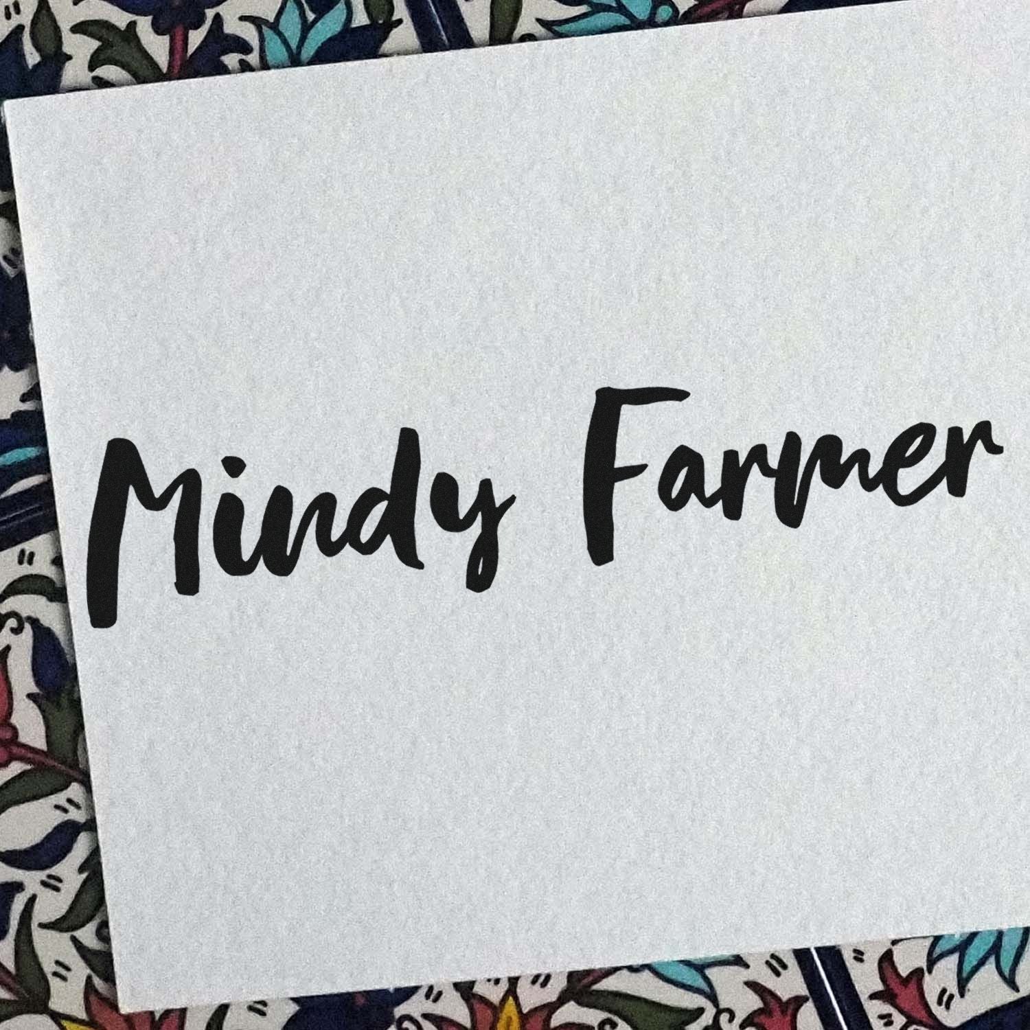 Black Mindy Farmer custom stamp seal on white paper, set against a colorful floral background.