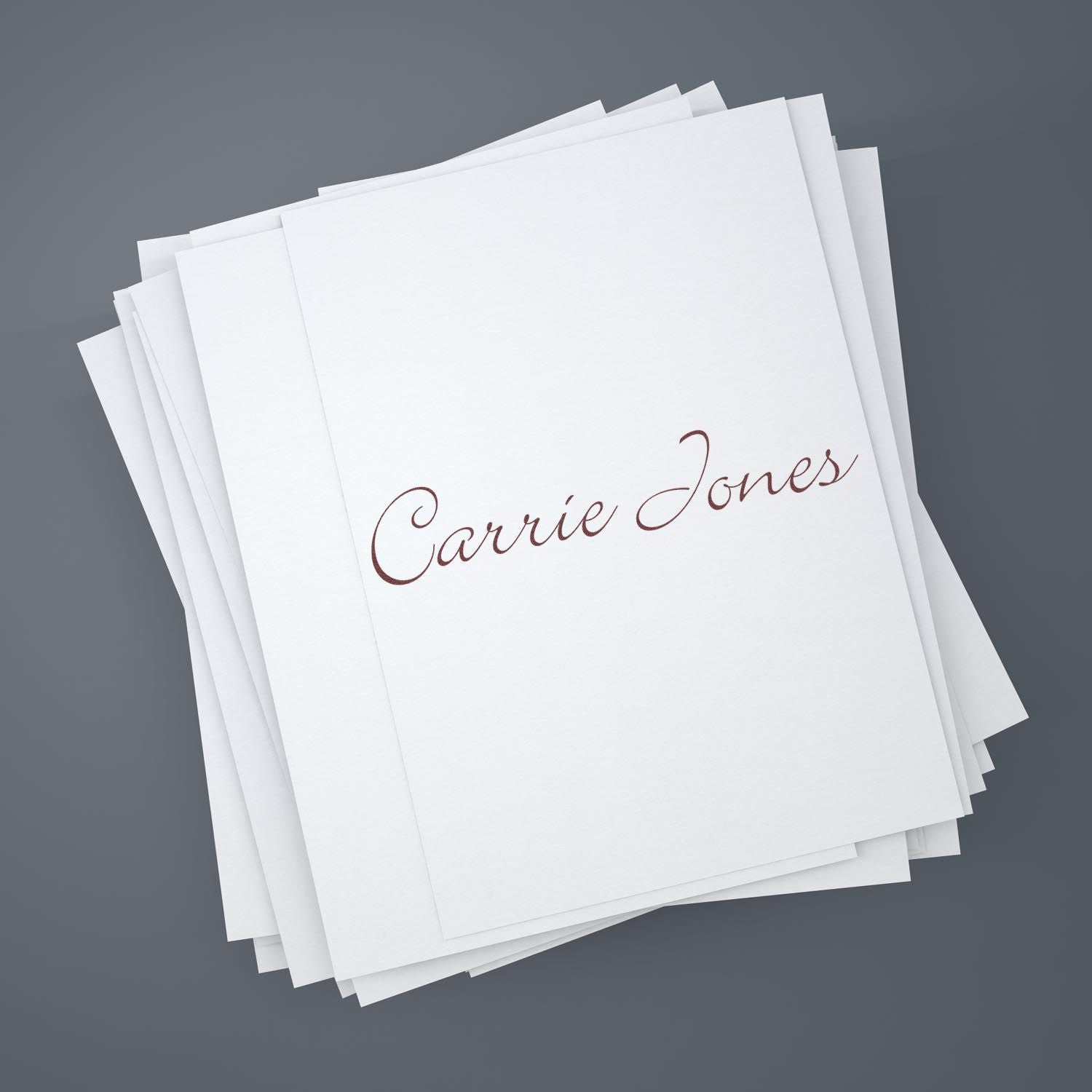 Stack of white custom stamp and seal stationery with brown script Carrie Jones on a gray background.