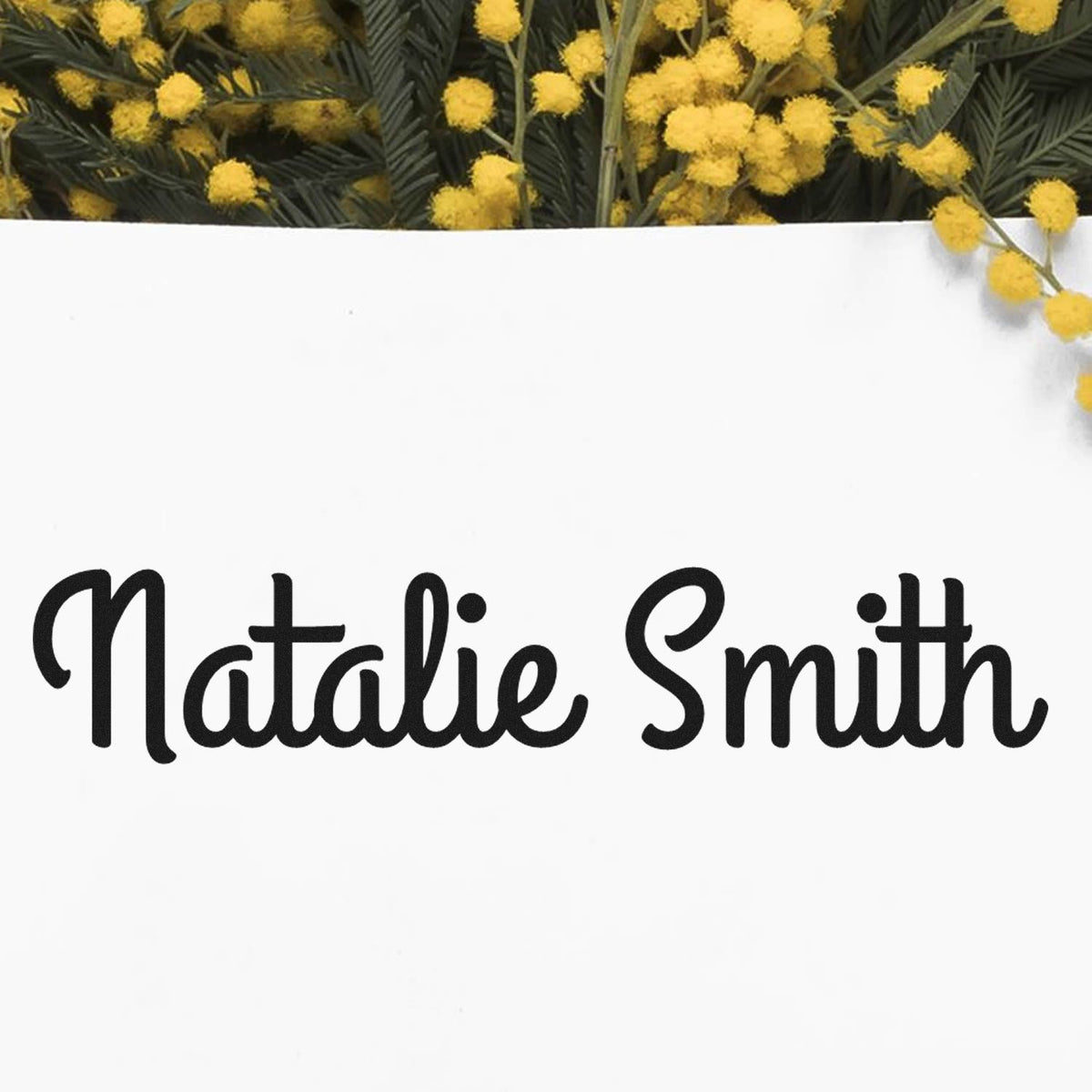 Black Natalie Smith stamp and seal on white card, framed by bright yellow mimosa flowers.