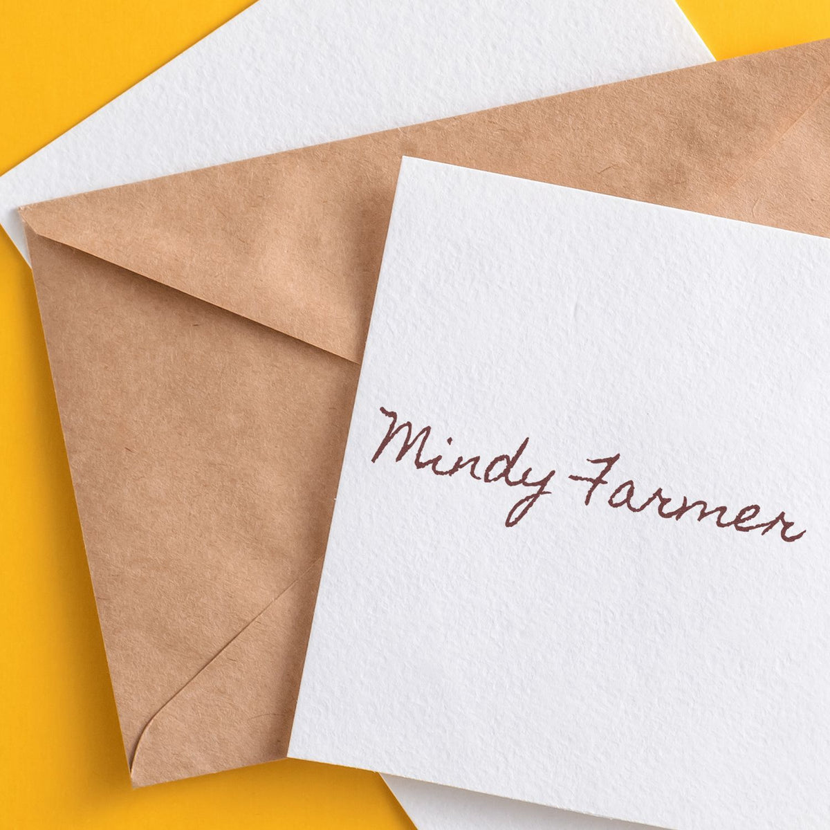 Custom stamp and seal products featuring handwritten Mindy Farmer on white and kraft envelopes, set against a yellow background.