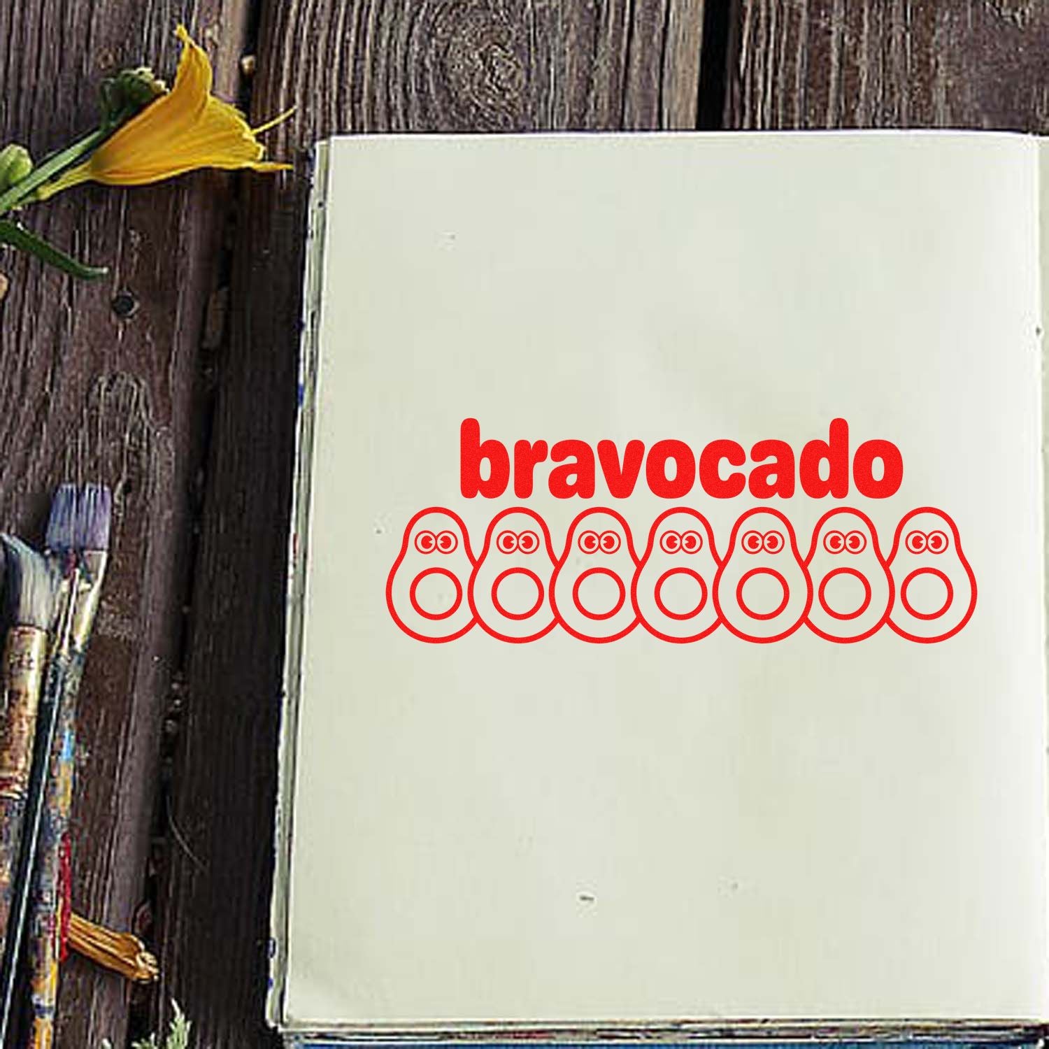 Cream stamp sheet with red bravocado text and seven red avocado-shaped seal icons on rustic wood.